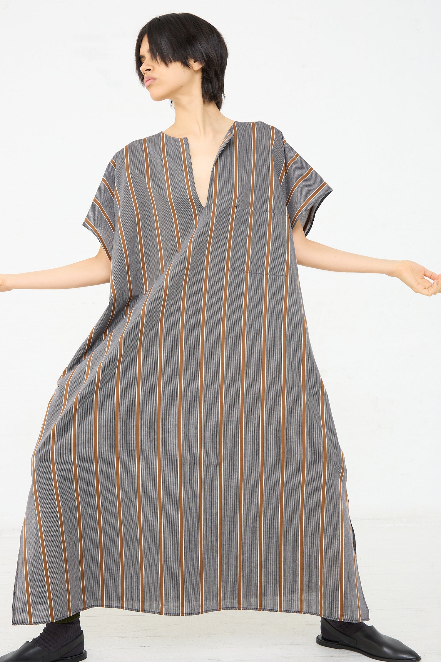 A woman wearing a lightweight Cristaseya Cotton Caftan in Striped Black and Noisette (Brown). Front view. 