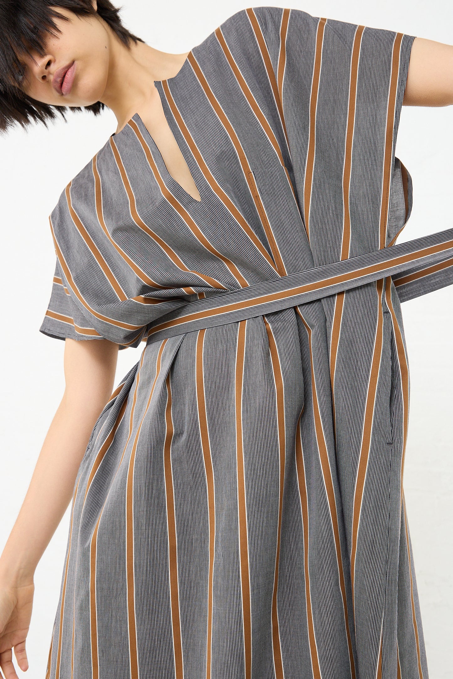 A woman wearing an oversized Cotton Caftan in Striped Black and Noisette (Brown) made by Cristaseya. Front view and up close.