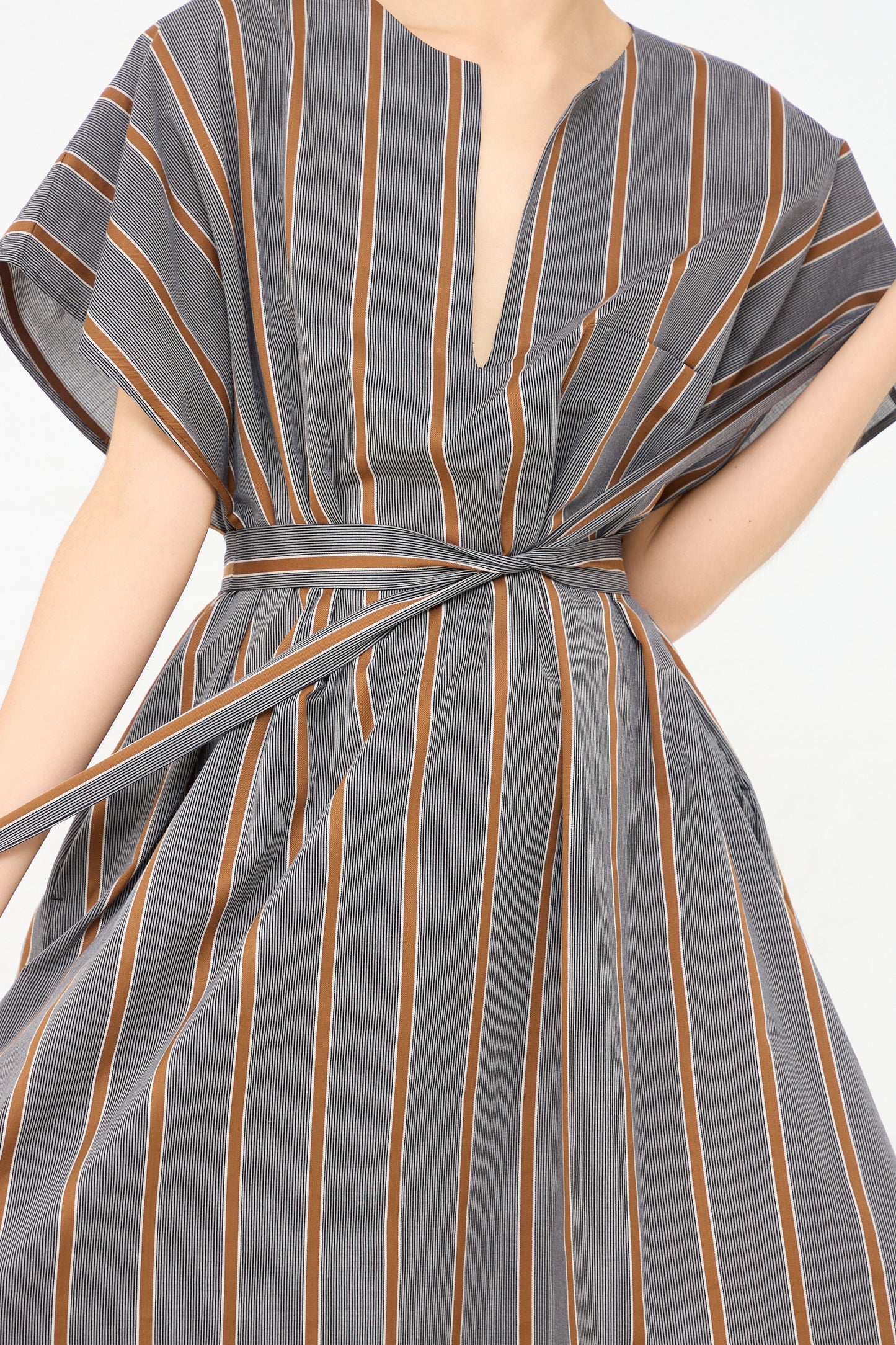 The model is wearing an oversized Cotton Caftan in Striped Black and Noisette (Brown) by Cristaseya. Up close view of fabric belt details.