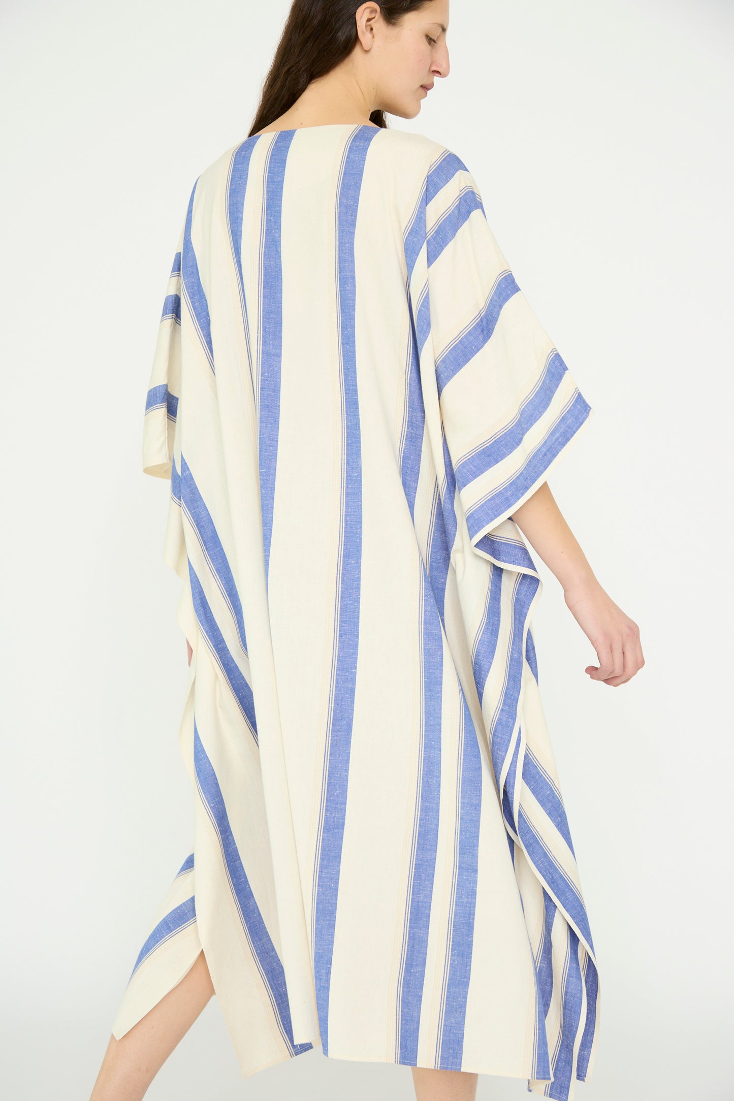 From behind, a person is draped in the Cristaseya Cotton Maxi Caftan, White with Blue Stripes, against a white background.