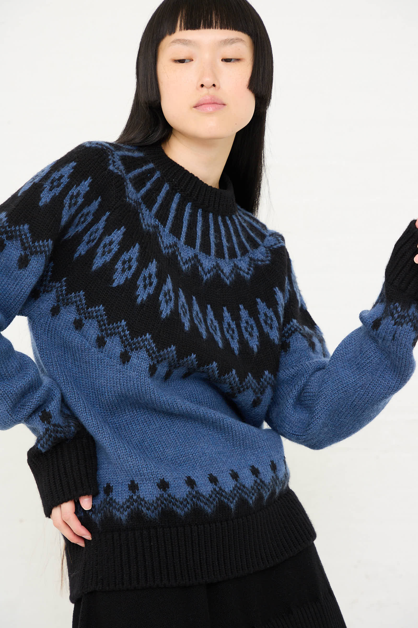 Person wearing the Cristaseya Extra Fine Merino Oversized Mountain Sweater in Black, featuring a subtle mountain motif, while posing with one hand on their hip.