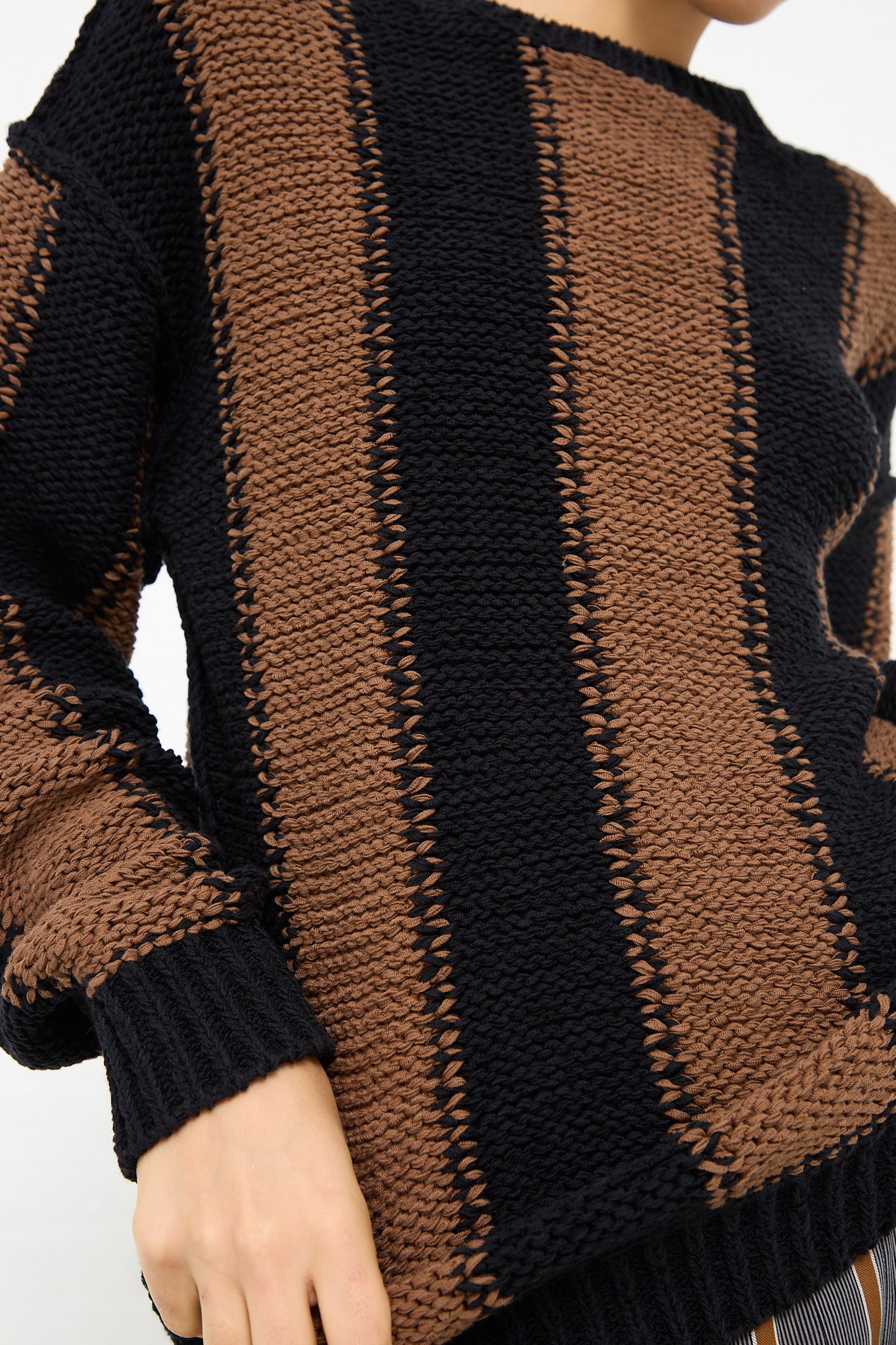 A woman wearing a Cristaseya Fettuccia Striped Sweater in Black and Noisette with dropped shoulders. Front view and up close.