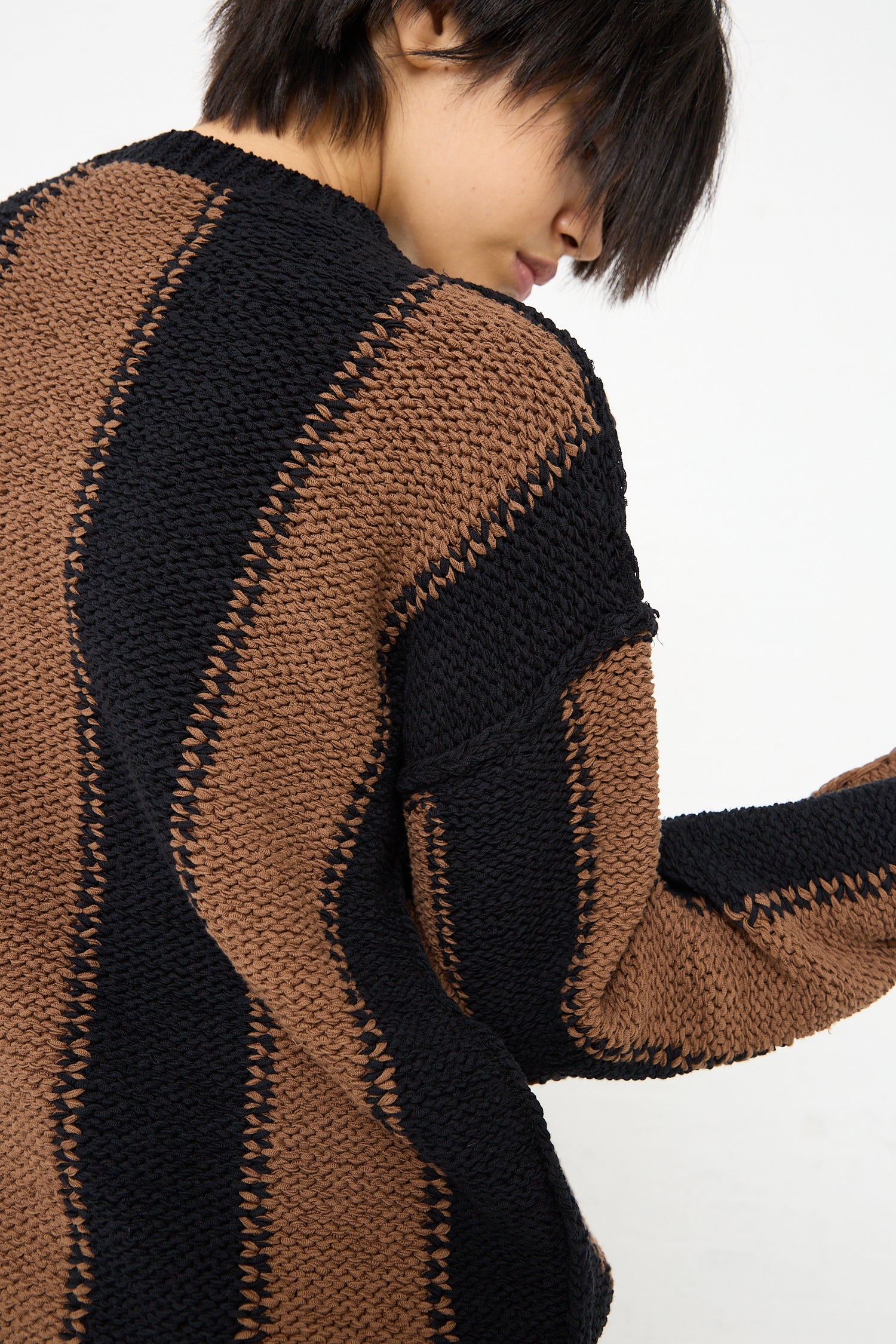 A woman wearing a Cristaseya Fettuccia Striped Sweater in Black and Noisette (Brown). Back view.