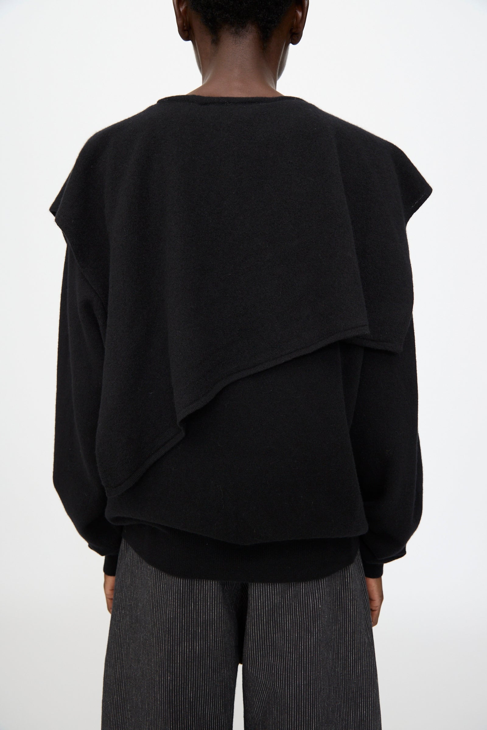 A person stands with their back to the camera, wearing Cristaseya's Flannel Sailor Collar Sweater in Black against a plain white background.