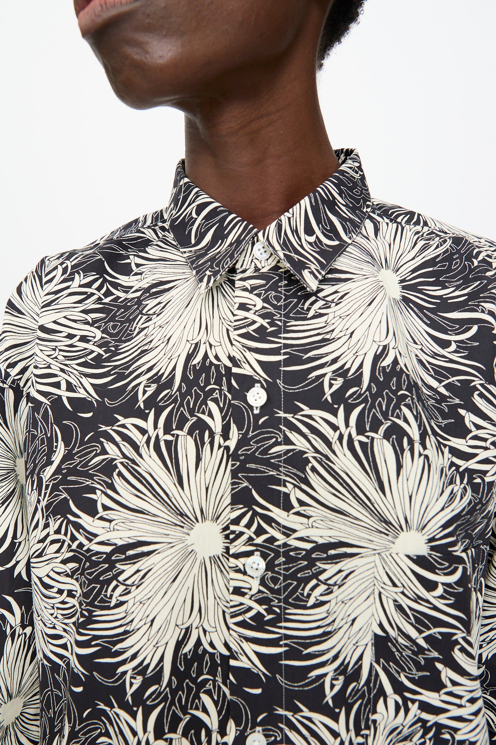A person wearing the Cristaseya Handmade Classic Collar Shirt in black with white flowers, shown from the shoulders up.