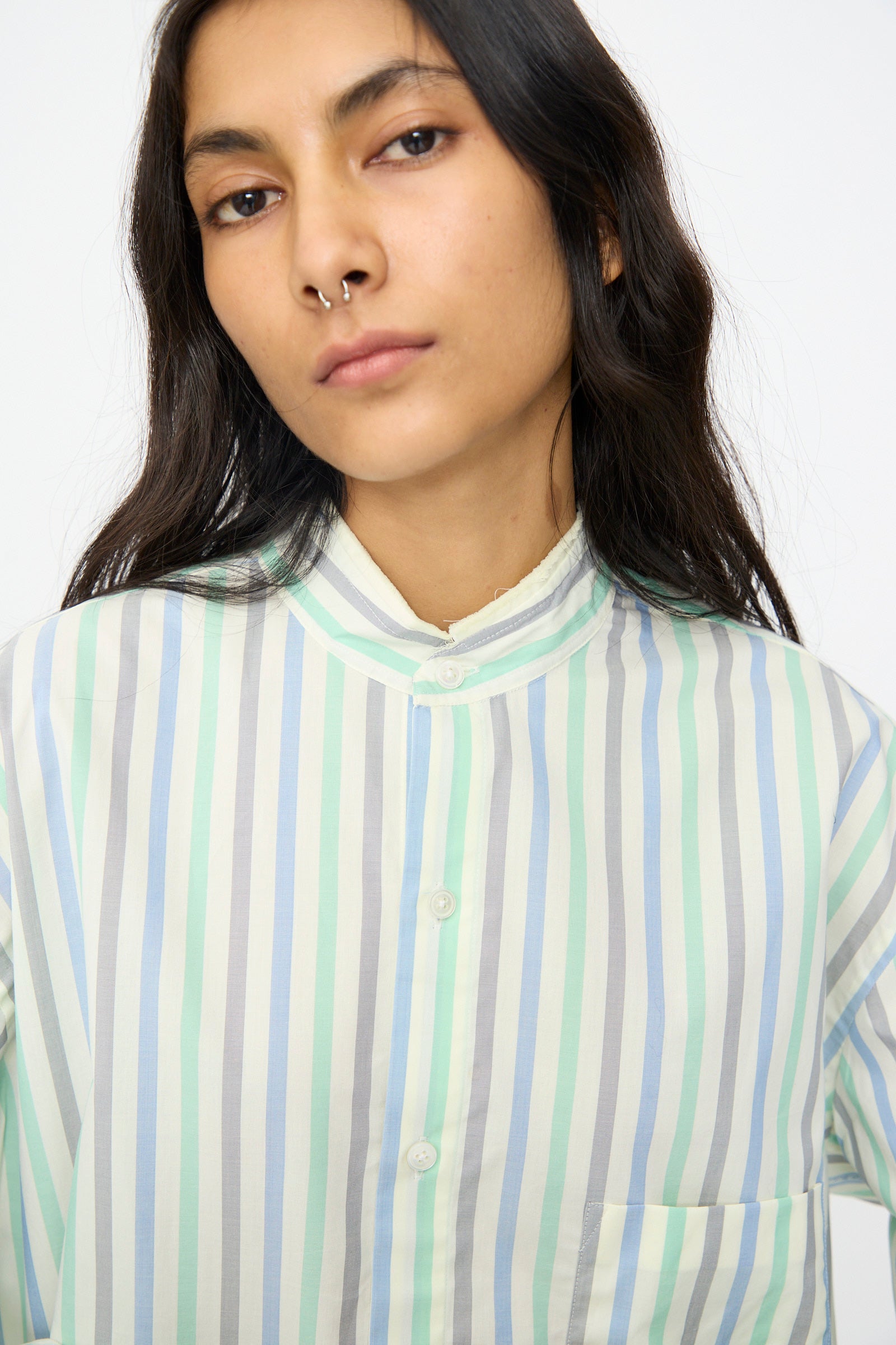 A person with long dark hair wears the Cristaseya Handmade Fringed Mao Collar Shirt in Striped Pastel Green and looks at the camera with a neutral expression.