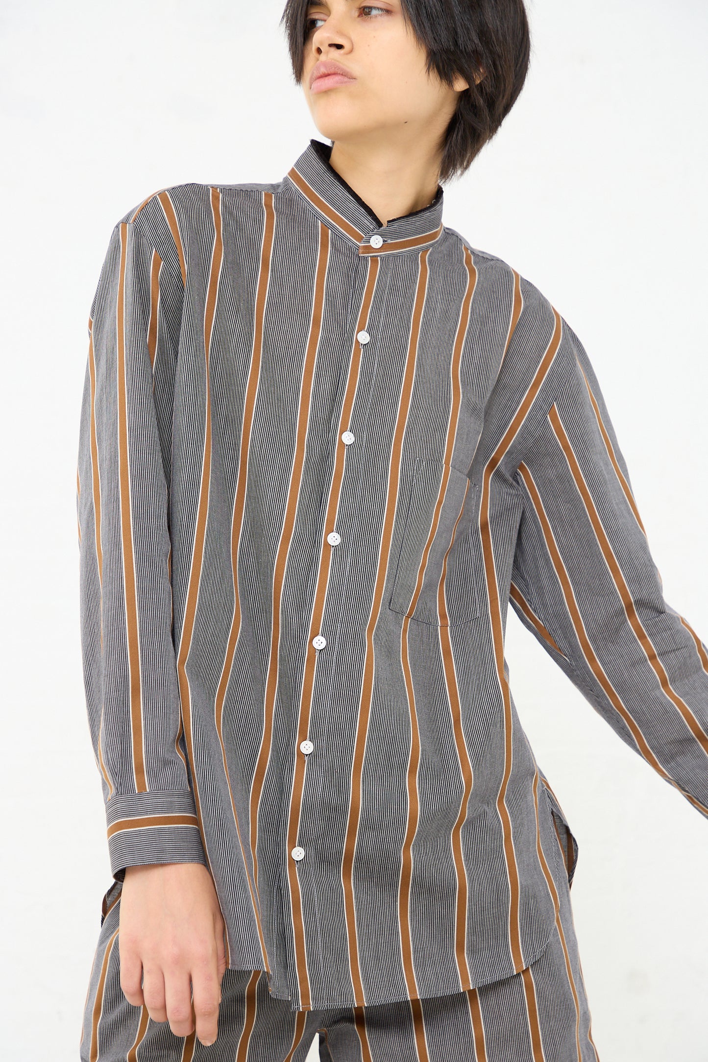 A woman wearing a lightweight, Cristaseya Mao Shirt with Fringed Collar in Striped Black and Noisette.
