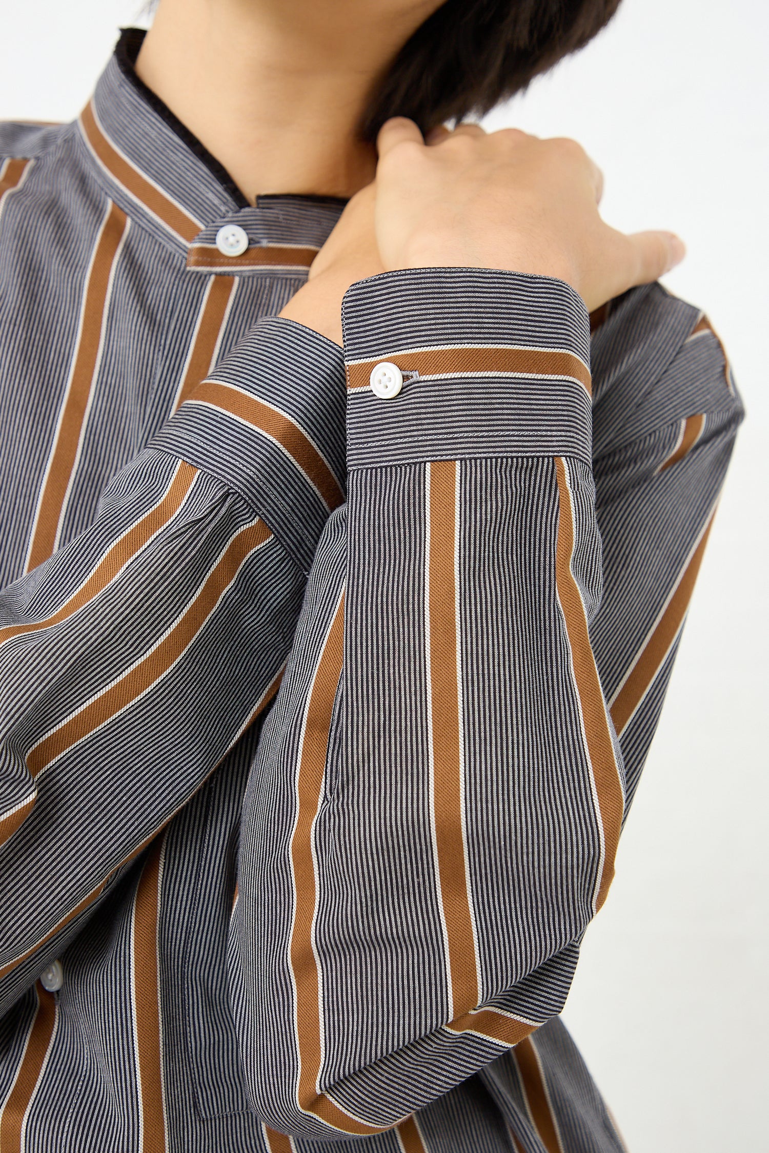 A woman wearing a Cristaseya Mao Shirt with Fringed Collar in Striped Black and Noisette made from Japanese cotton.