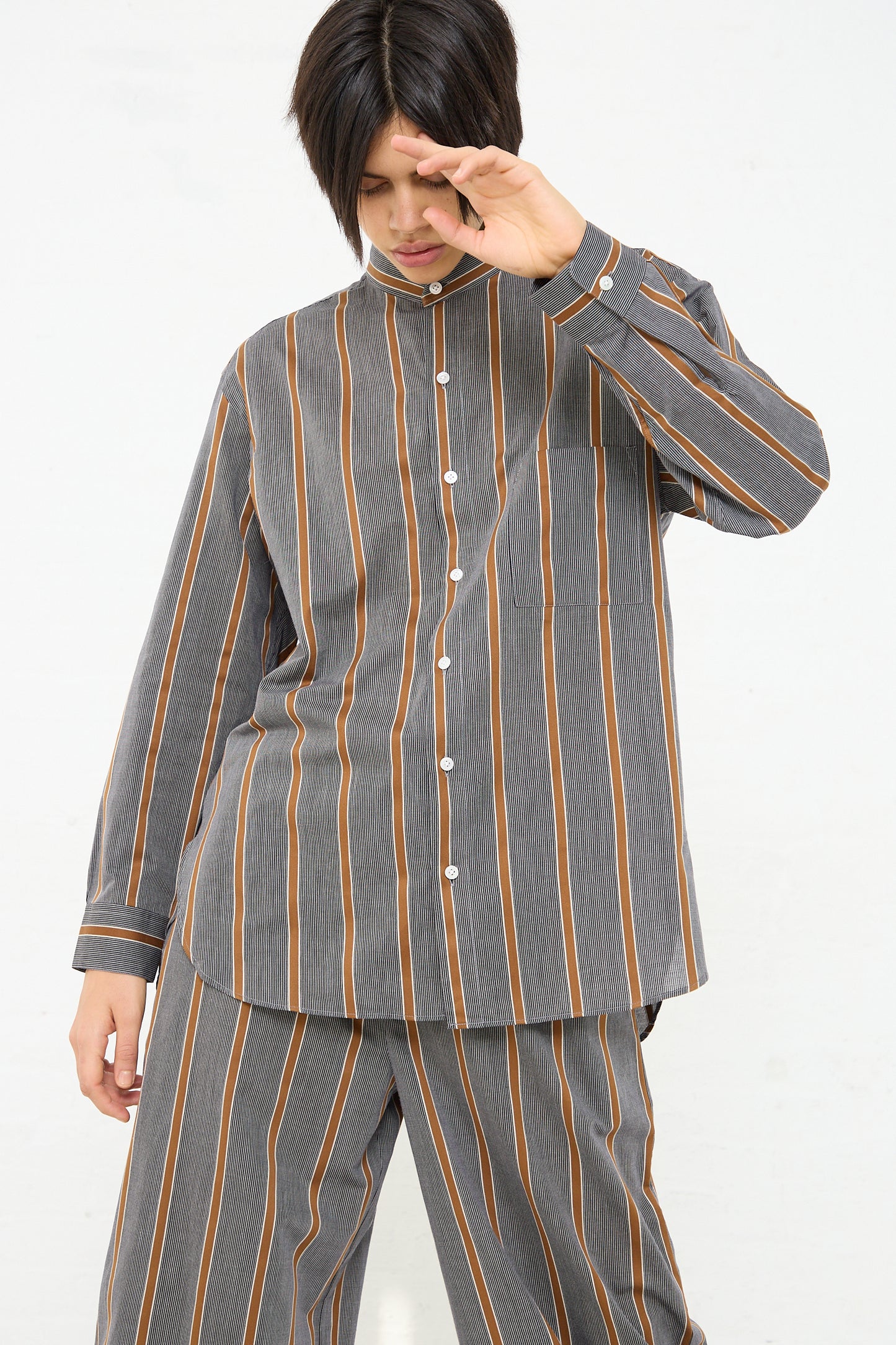 A man wearing a Cristaseya Mao Shirt with Fringed Collar in Striped Black and Noisette. Front view.