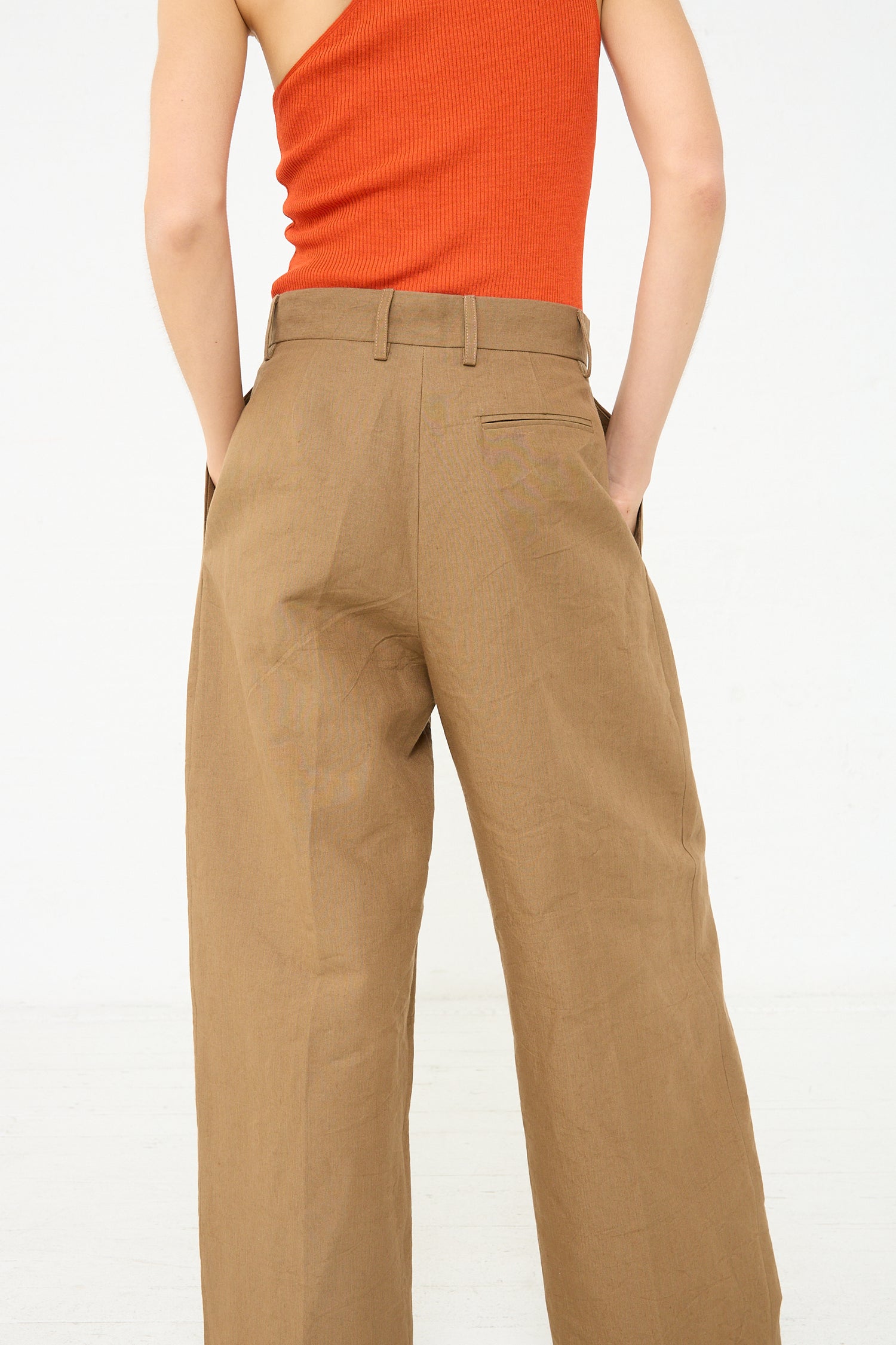 The back view of a woman wearing Cristaseya's Japanese Washi and Linen Canvas Double Pleated Wide Trouser in Mocha.