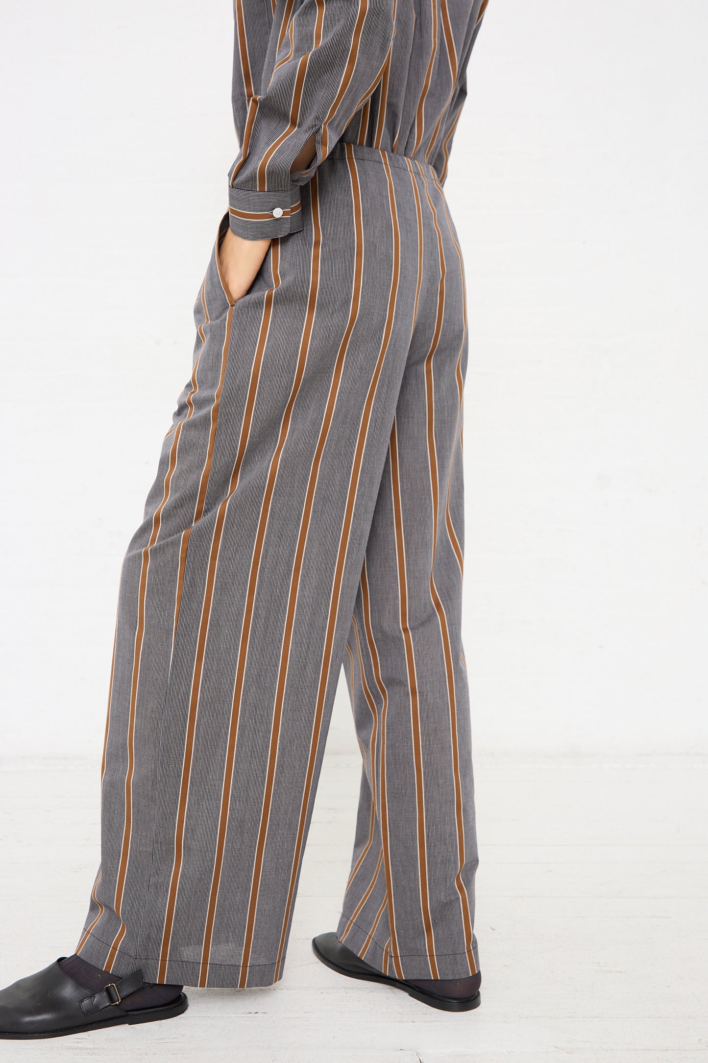 The side of a woman wearing an oversized Maxi Large Pant in Striped Black and Noisette jumpsuit made of lightweight Japanese cotton by Cristaseya.