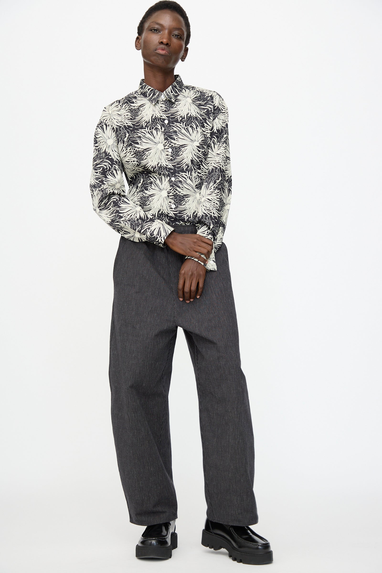 A person stands against a plain background wearing Cristaseya Moroccan Pyjama Pants in black with white stripes.