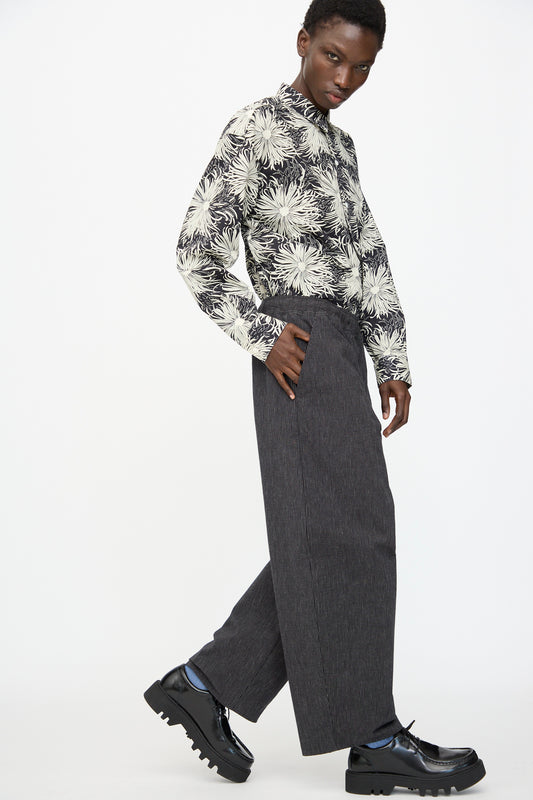 A person wears a floral long-sleeve shirt, Cristaseya Moroccan Pyjama Pants in Black with White Stripes, and black platform shoes, posing against a plain white background.