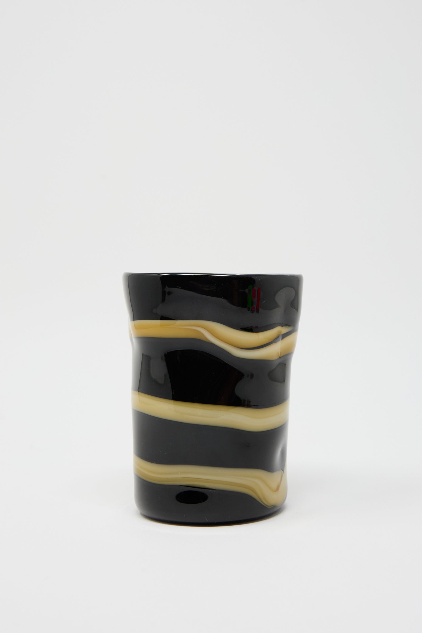 A Murano Glass cup in black with an ocher stripe encircling it, by Cristaseya, set against a plain white background.