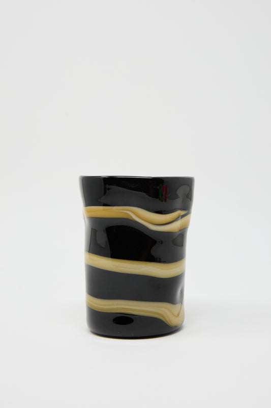 A Murano Glass cup in black with an ocher stripe encircling it, by Cristaseya, set against a plain white background.