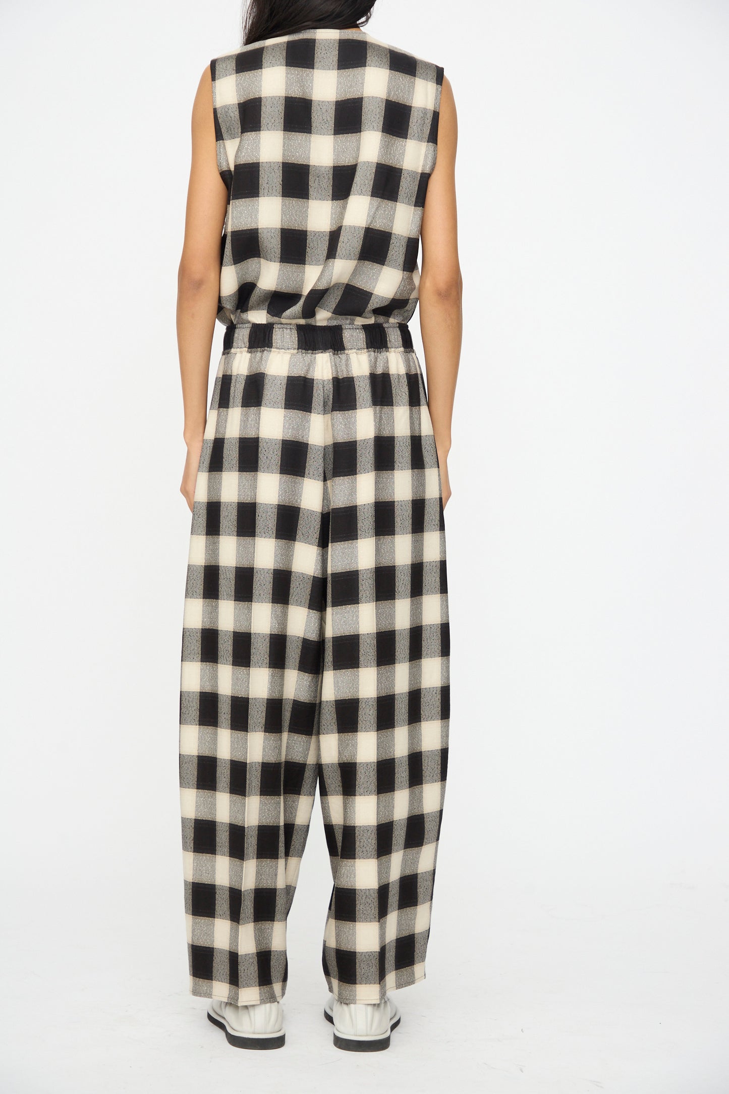 Person wearing Cristaseya's Oversized Pyjama Pants in Black and Cream Checks, styled with white shoes, photographed from the back against a plain background.