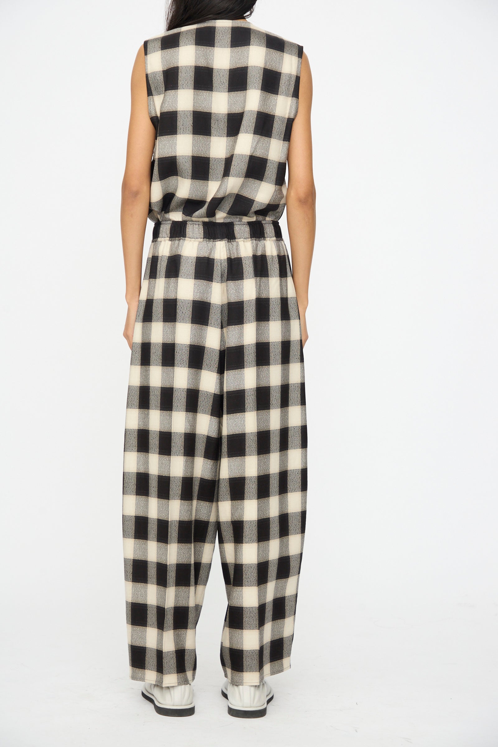 Person wearing Cristaseya's Oversized Pyjama Pants in Black and Cream Checks, styled with white shoes, photographed from the back against a plain background.