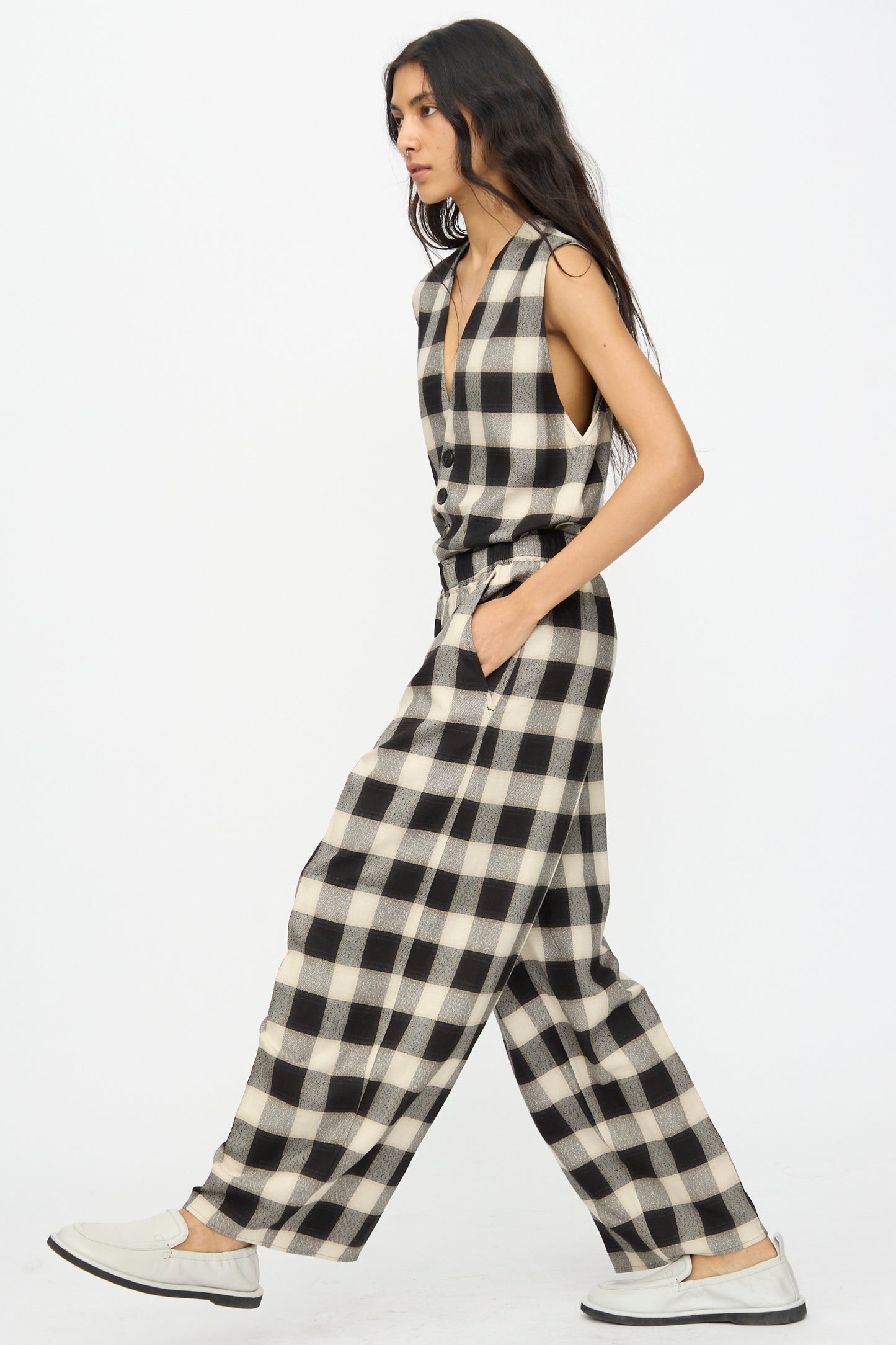 A person walks in profile wearing Cristaseya's Oversized Pyjama Pants in Black and Cream Checks and slip-on white shoes.