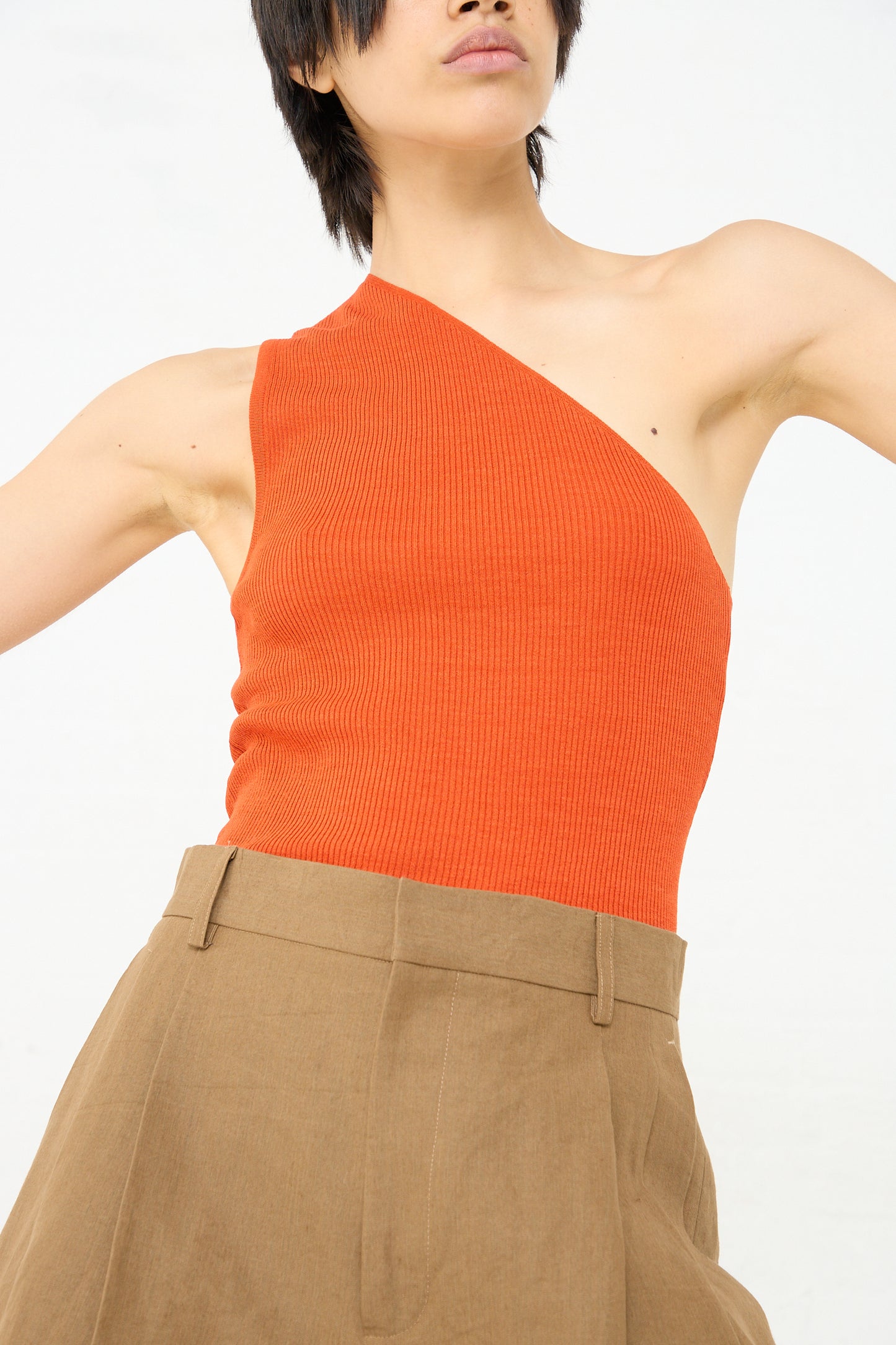 A woman in a Ribbed Silk Asymmetrical Top in Orange by Cristaseya.