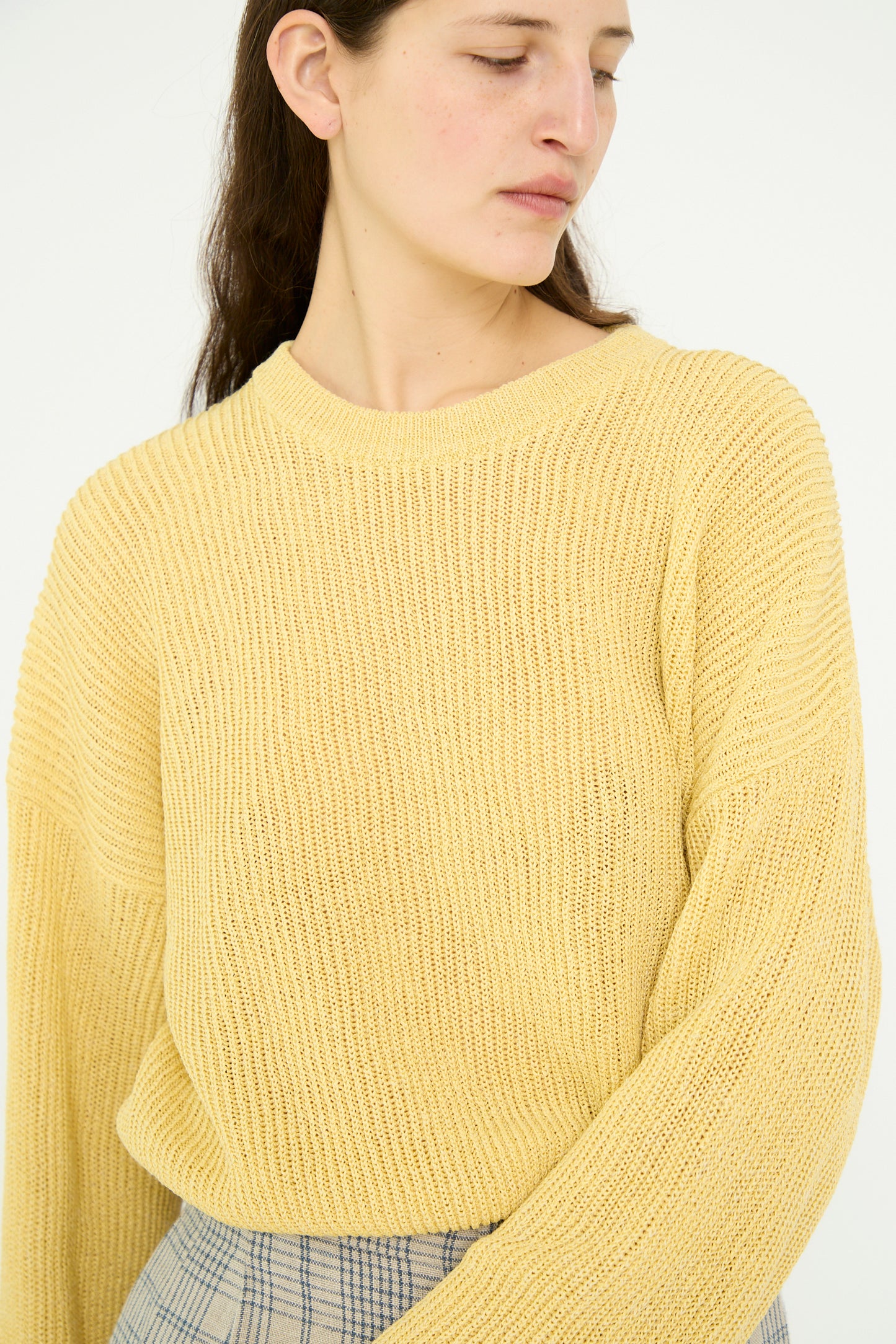 A model in a Washi Paper Dropshoulder Cropped Sweater in Yellow by Cristaseya and a plaid pant stands against a plain background, looking to the side.