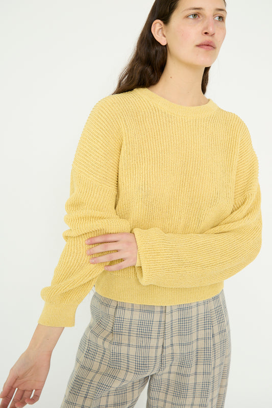 A person in Cristaseya's Washi Paper Dropshoulder Cropped Sweater in Yellow and plaid pants stands against a plain white background.