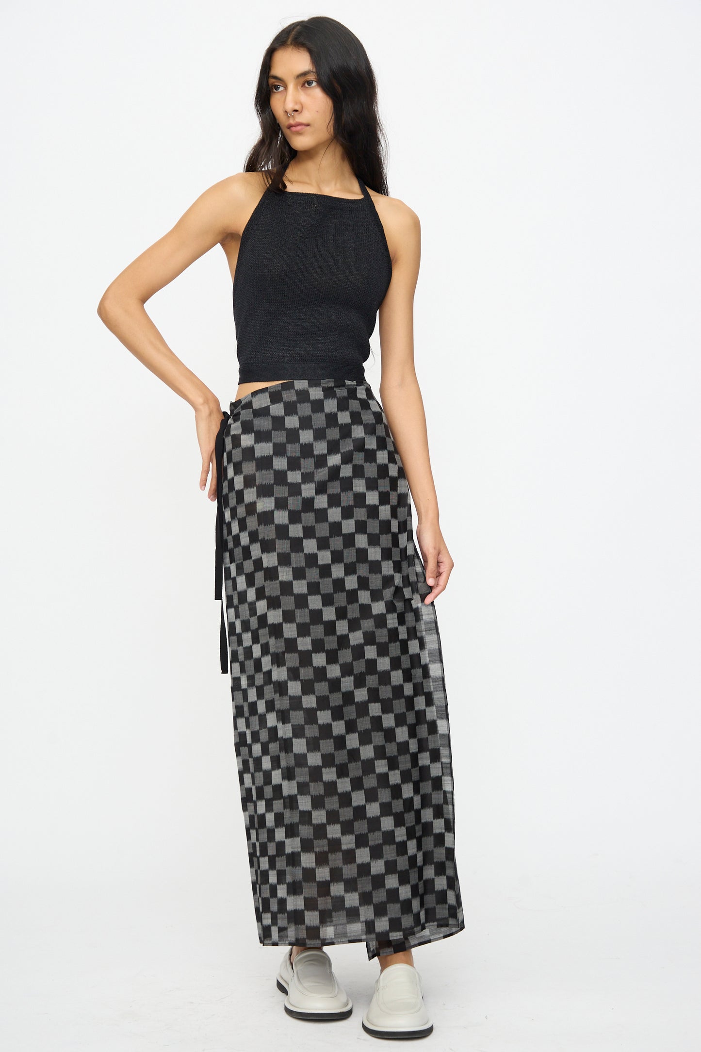 A woman wears the Cristaseya Washi Paper Summer Top in Black, paired with a black and gray checkered maxi skirt and white shoes, standing against a plain white background.