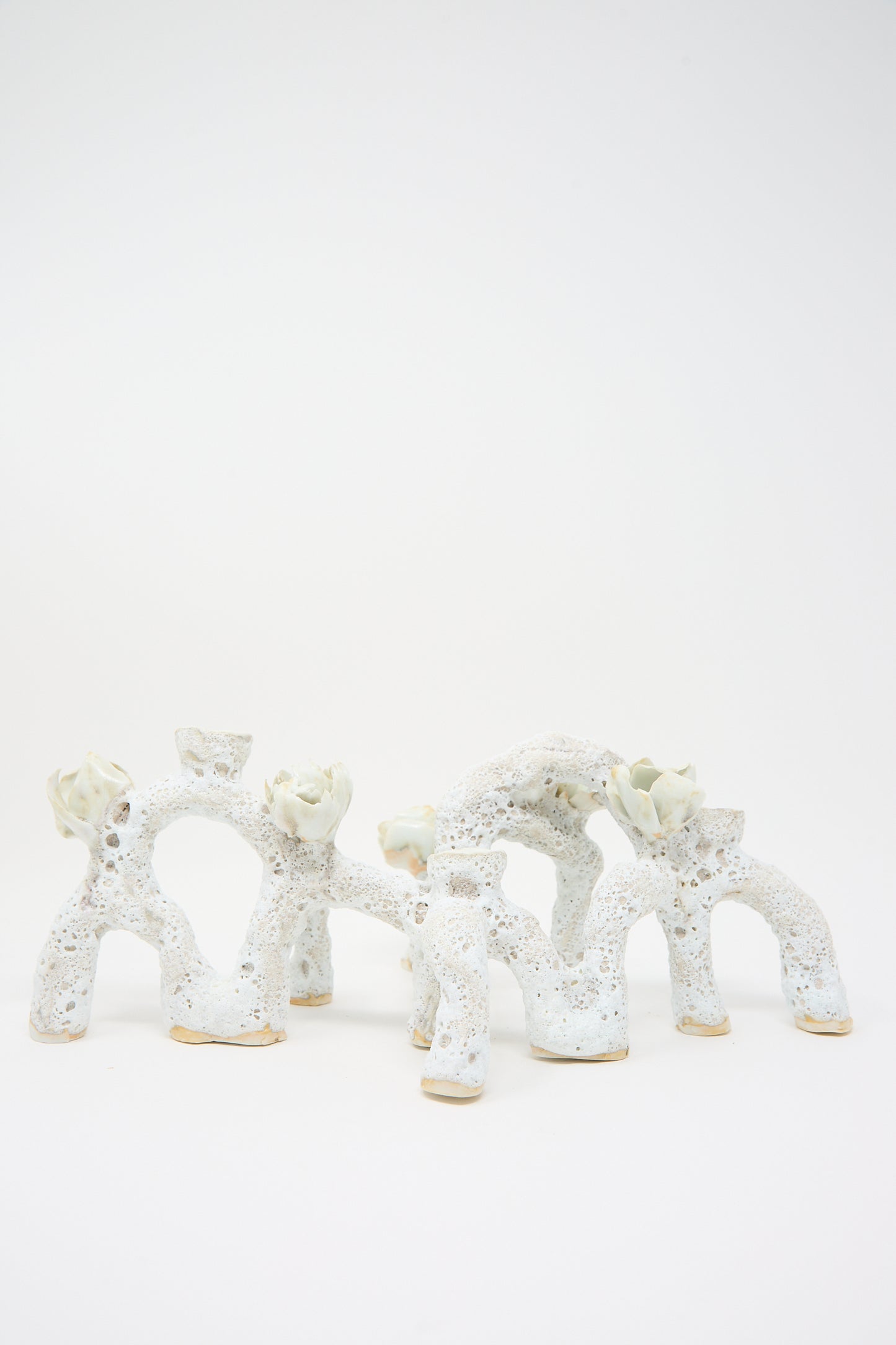 A photo of an abstract ceramic sculpture with arch-like shapes and textured surfaces, reminiscent of the Blooming Arches Candle Holder by Dear You, set against a plain white background.