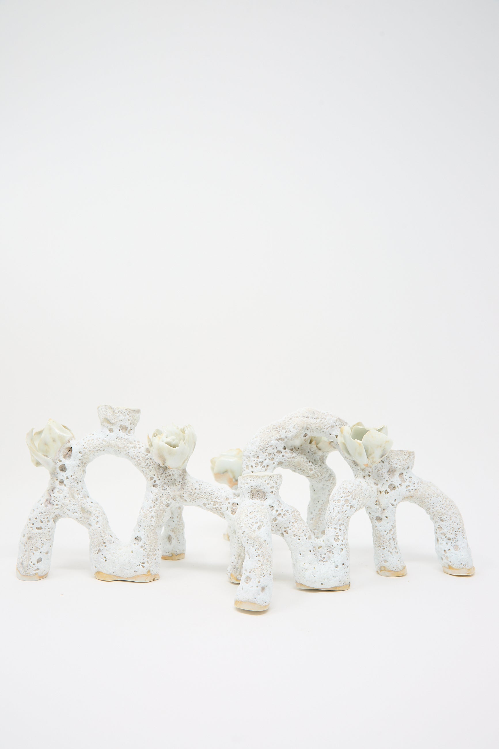 A photo of an abstract ceramic sculpture with arch-like shapes and textured surfaces, reminiscent of the Blooming Arches Candle Holder by Dear You, set against a plain white background.