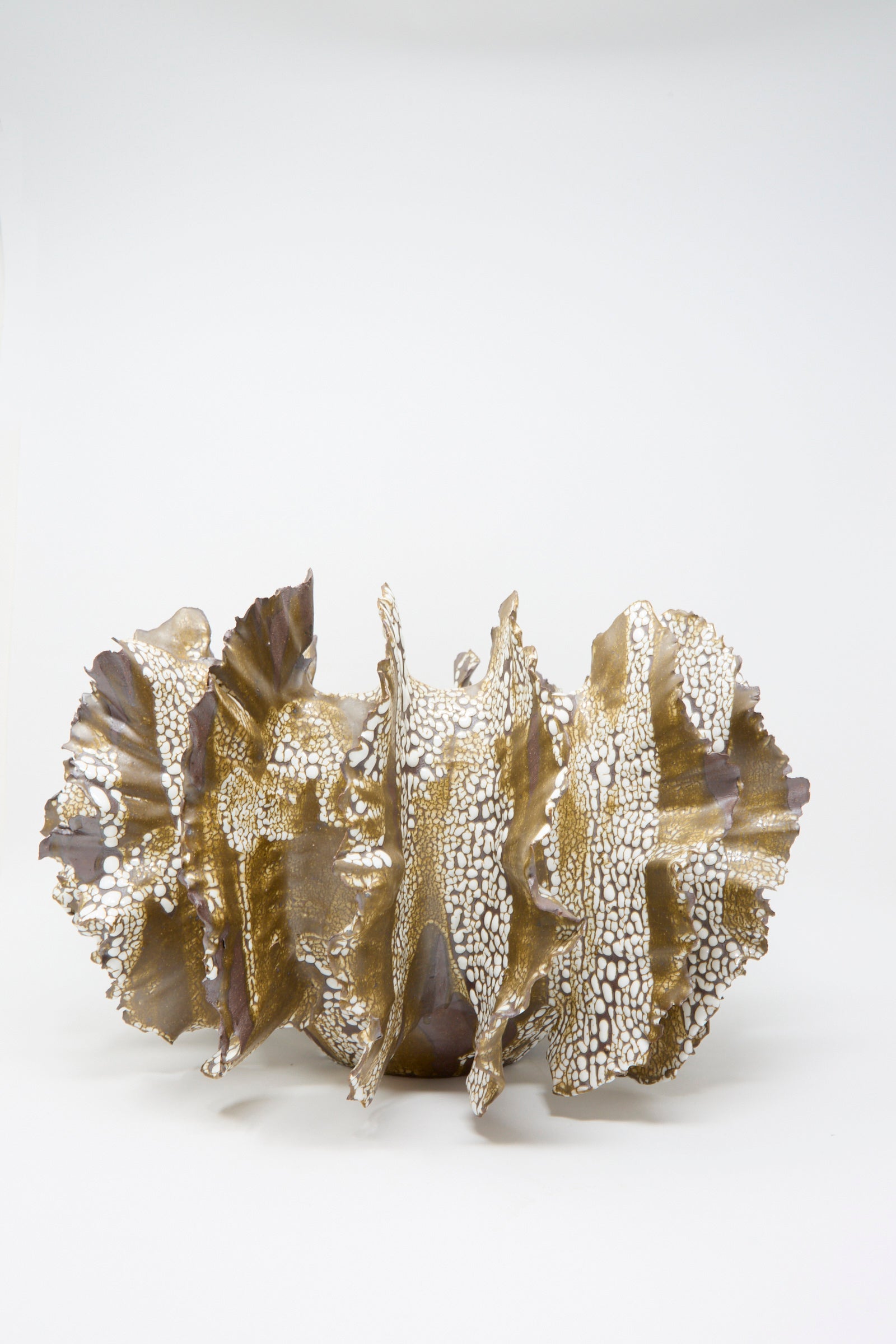 The "Wild Petal N. 10" by Dear You is an abstract ceramic sculpture with a textured glaze. It features wavy, gold and white surfaces resembling an organic form against a plain background.