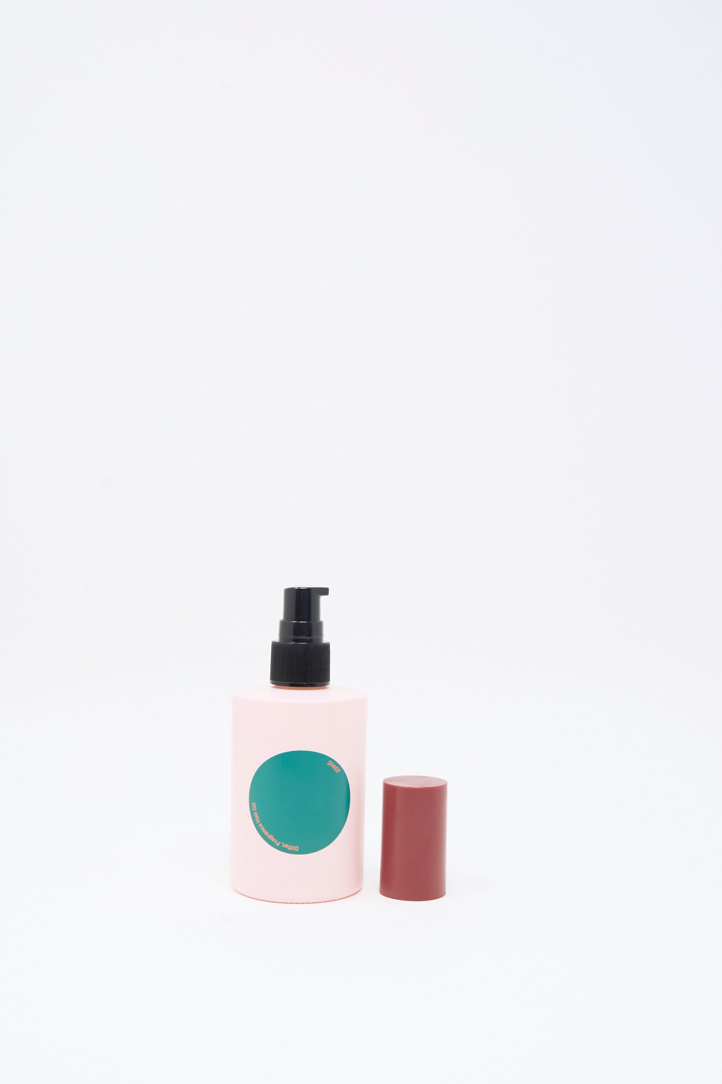 A pink bottle of Diffar Herbal Floral Fragrance Oil, featuring a green label and a black pump dispenser, stands next to its removed maroon cap on a white background.