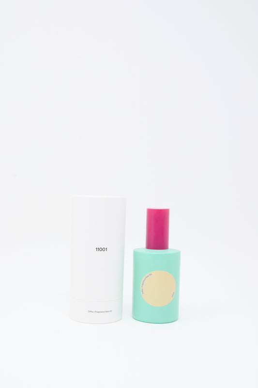A teal bottle of Diffar Tokyo Balance Fragrance Oil with a yellow circle label and pink cap stands next to a white cylindrical box labeled "11001" against a white background, featuring plant-based essential oils.