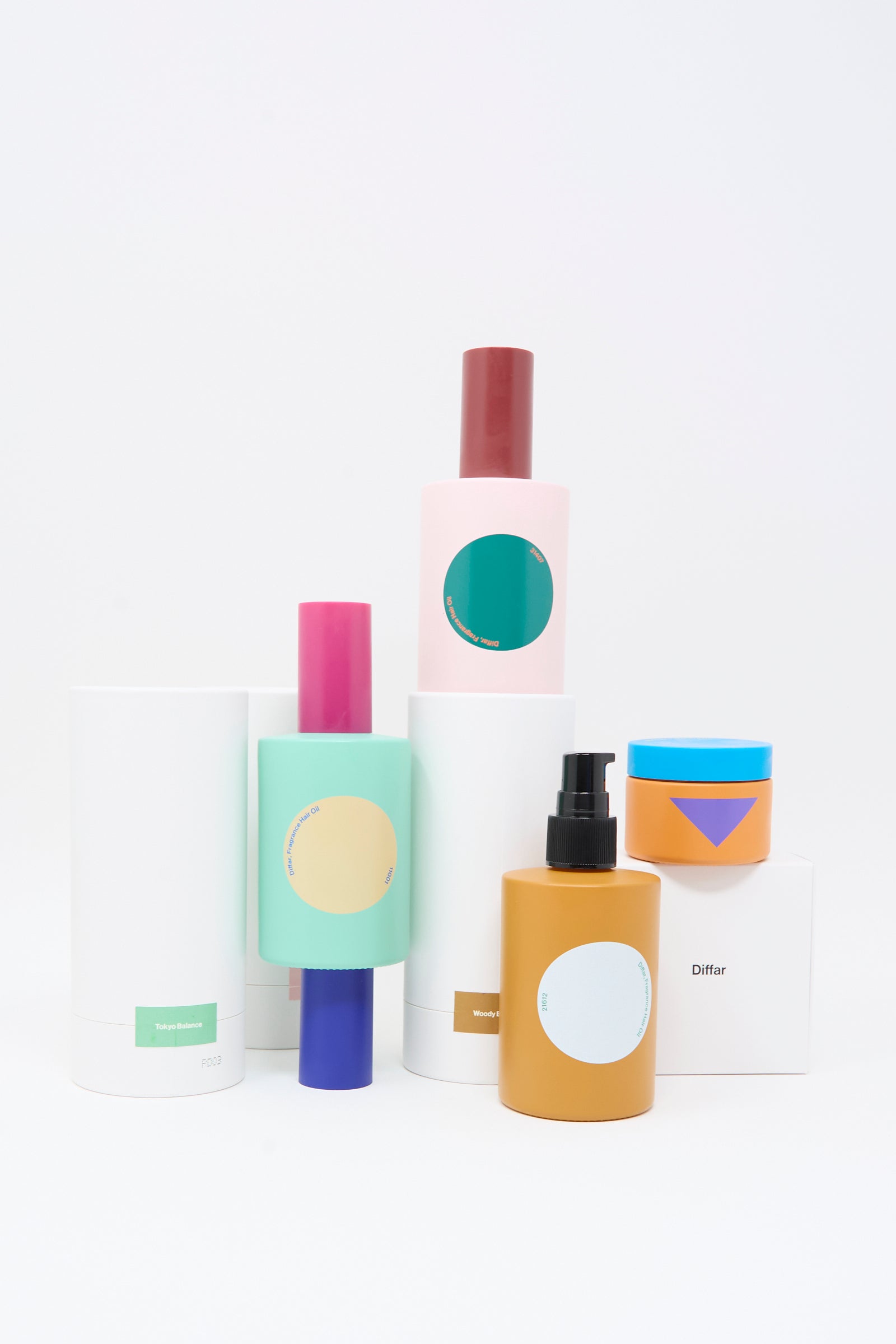Diffar Woody Earthy Fragrance Oil bottles and jars—with minimal, colorful labels that highlight their plant-based essential oils—are arranged on a white background.