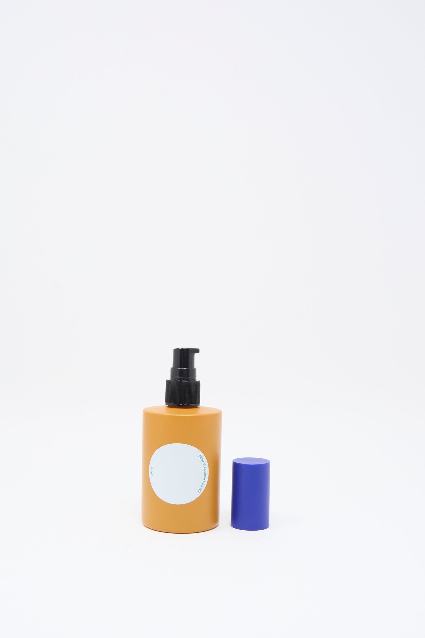 A yellow pump bottle of Diffar Woody Earthy Fragrance Oil with a blank white label stands next to a blue cap on a plain white background.