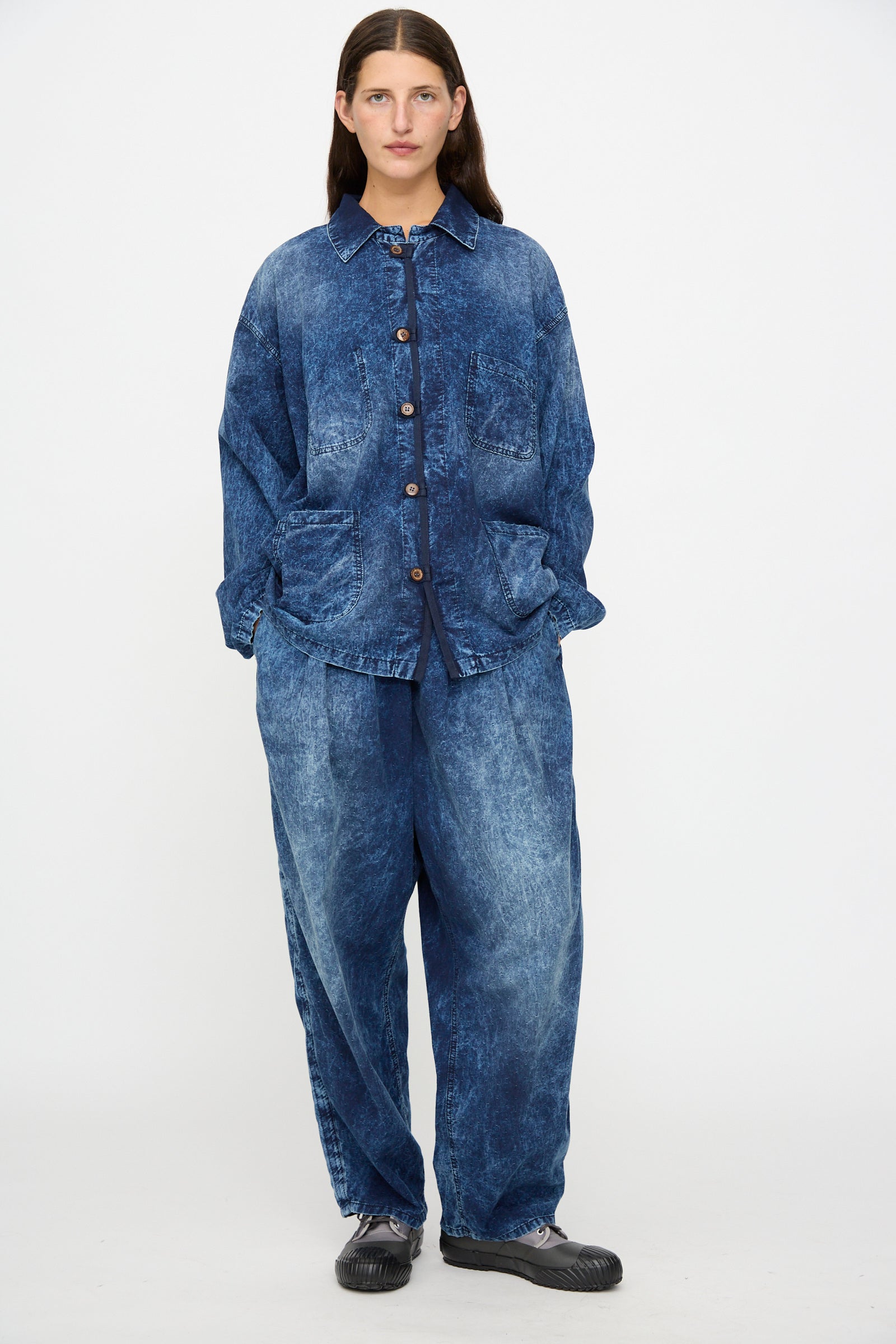 A person stands against a white background, wearing the Dr. Collectors 6 oz. Cotton New Saigon Shirt Jacket in Indigo with matching wide-leg jeans and black shoes.