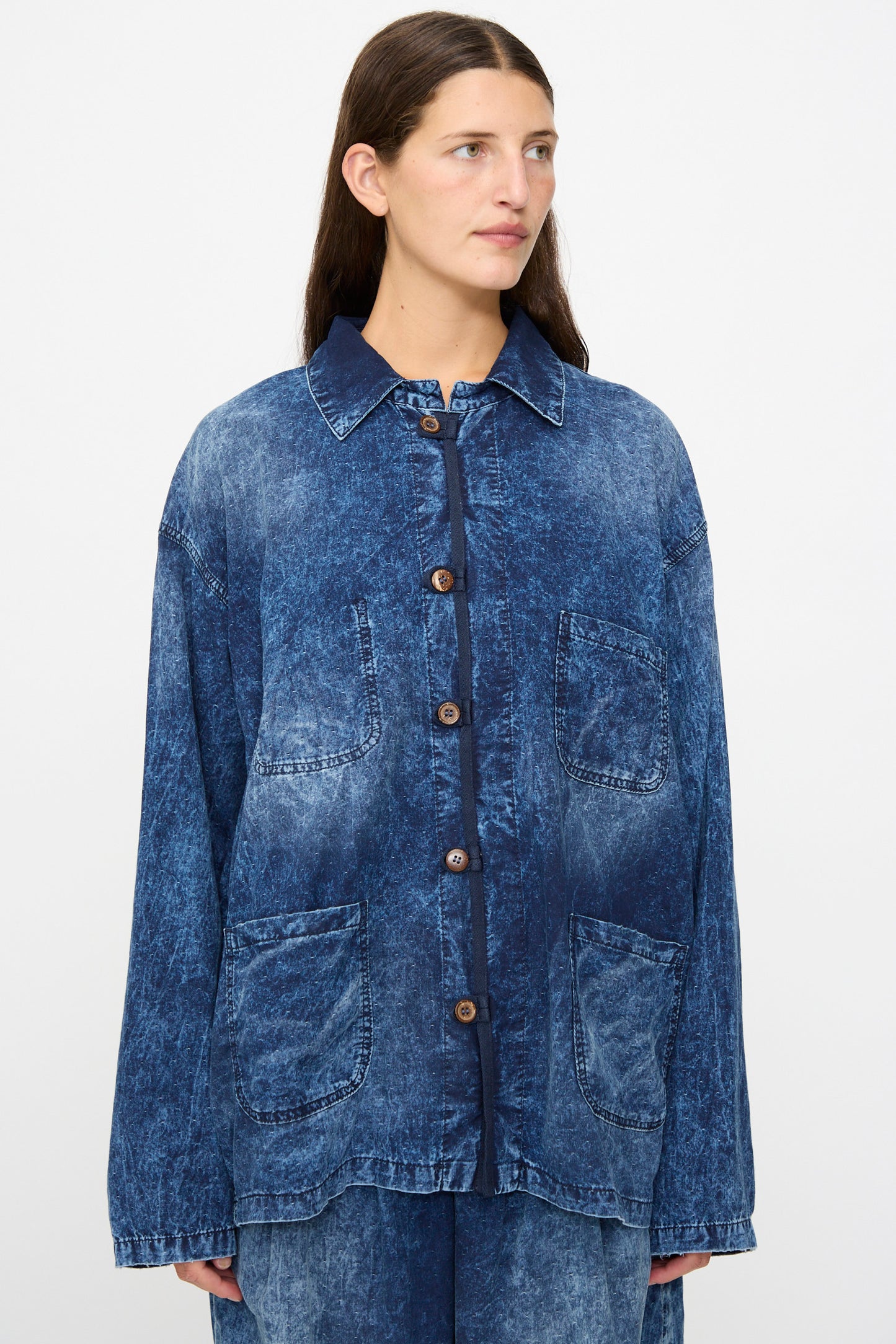 A person wears the Dr. Collectors 6 oz. Cotton New Saigon Shirt Jacket in Indigo—an oversized, acid-wash denim workwear style crafted from indigo cotton with front buttons and four large pockets—while standing against a plain background.