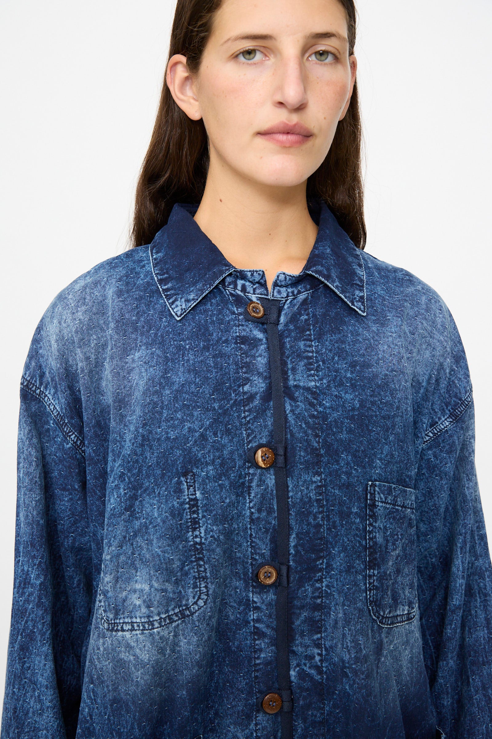 A person wearing the Dr. Collectors 6 oz. Cotton New Saigon Shirt Jacket in Indigo, featuring a button-up front, collar, and chest pocket, stands against a plain white background.