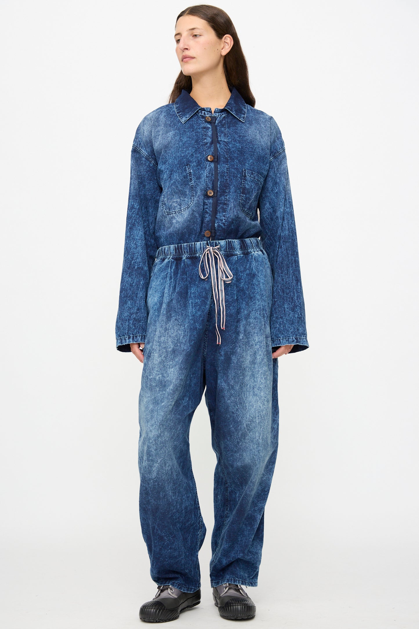 A person wearing Dr. Collectors’ 6 oz. Cotton P43 Kyoto Pant in Sunfaded Indigo, paired with black shoes and standing against a plain white background.