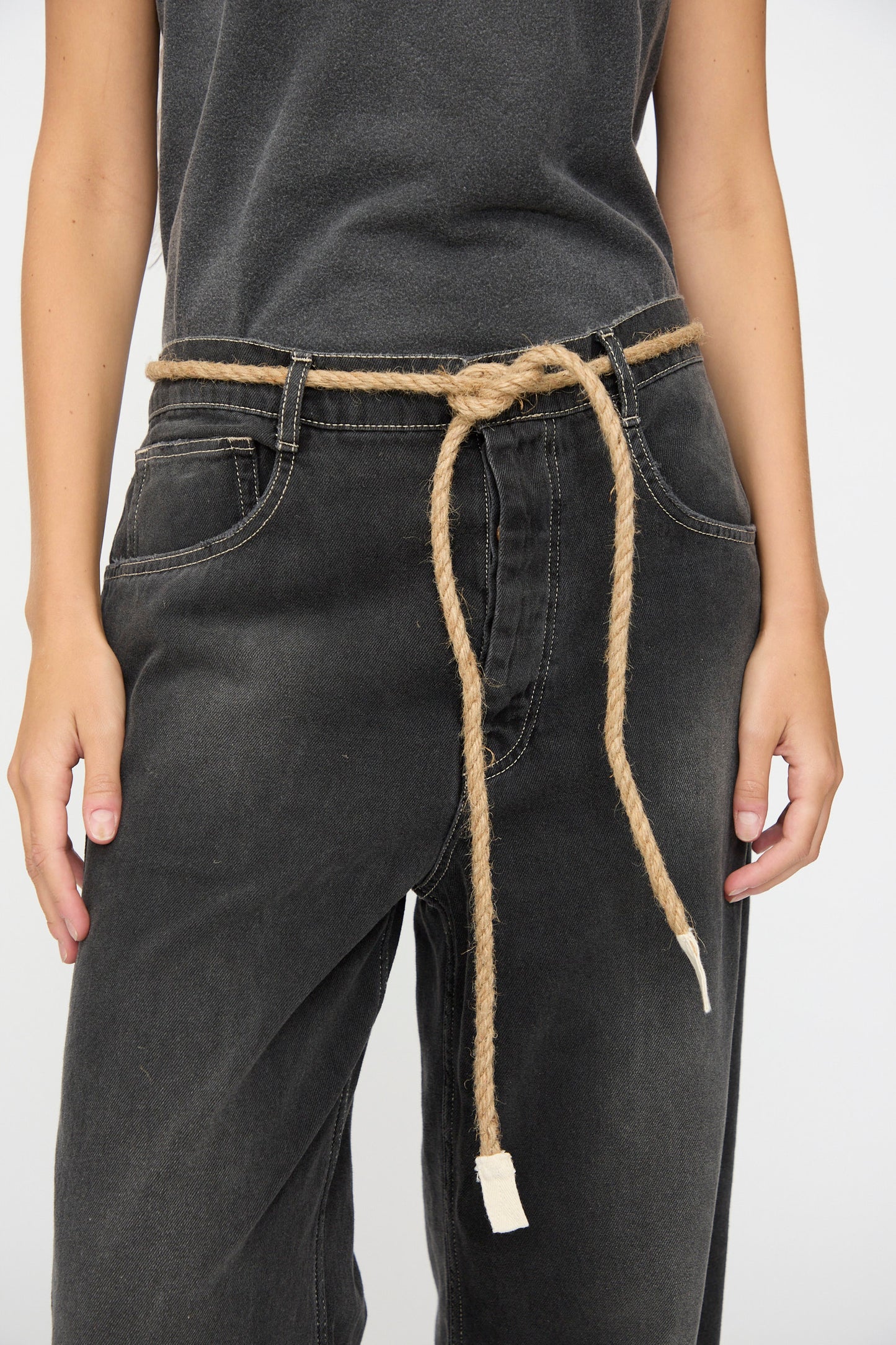 A person wearing Dr. Collectors’ 9 oz. Denim P84 Dungaree Pant in Sunfaded Black, paired with a dark shirt and accessorized with a braided hemp rope belt tied around the waist.