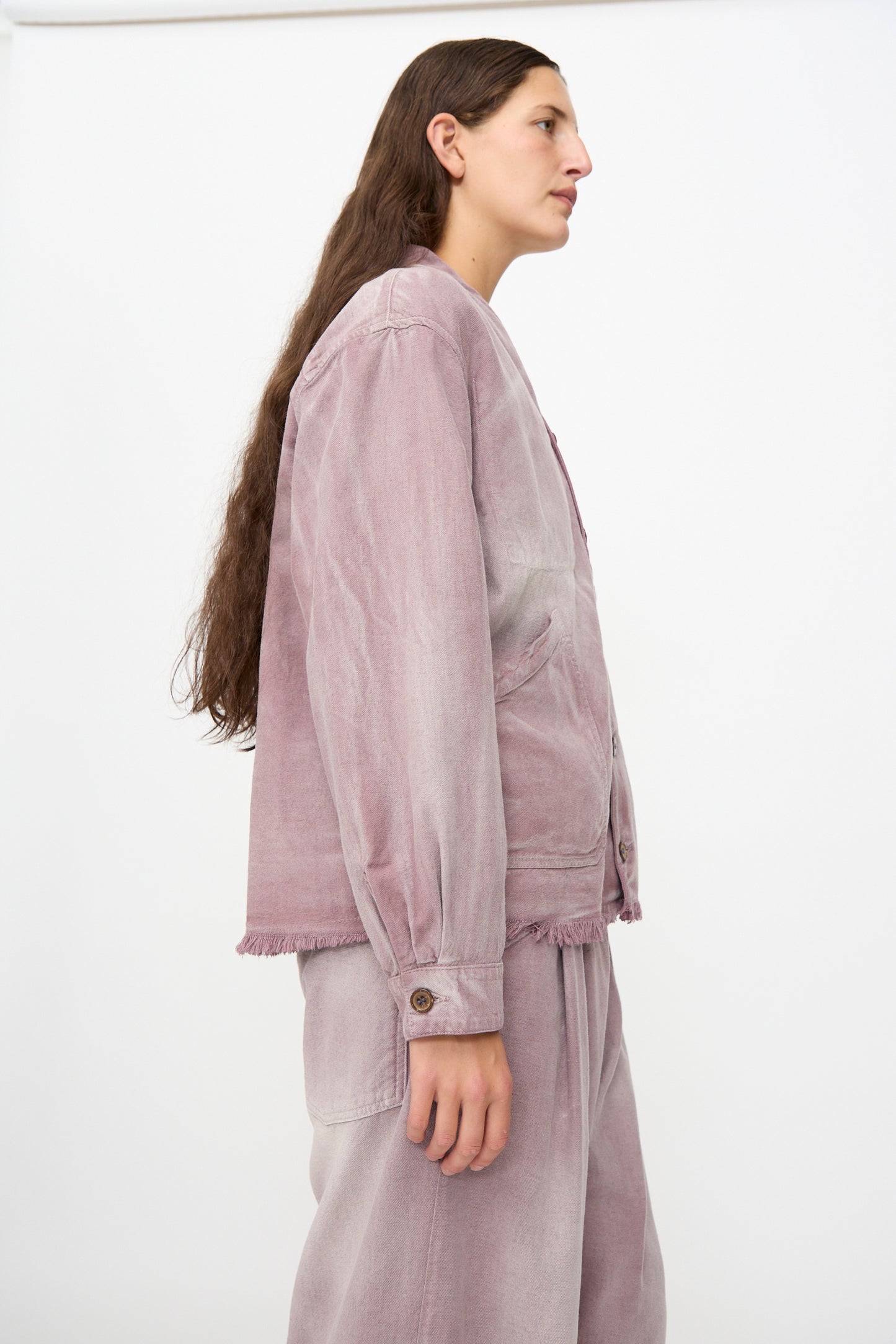 A person with long brown hair stands in profile against a plain white background, wearing the Dr. Collectors 9 oz. Okinawa Jacket in Sunfaded Dusty Orchid with matching pants.