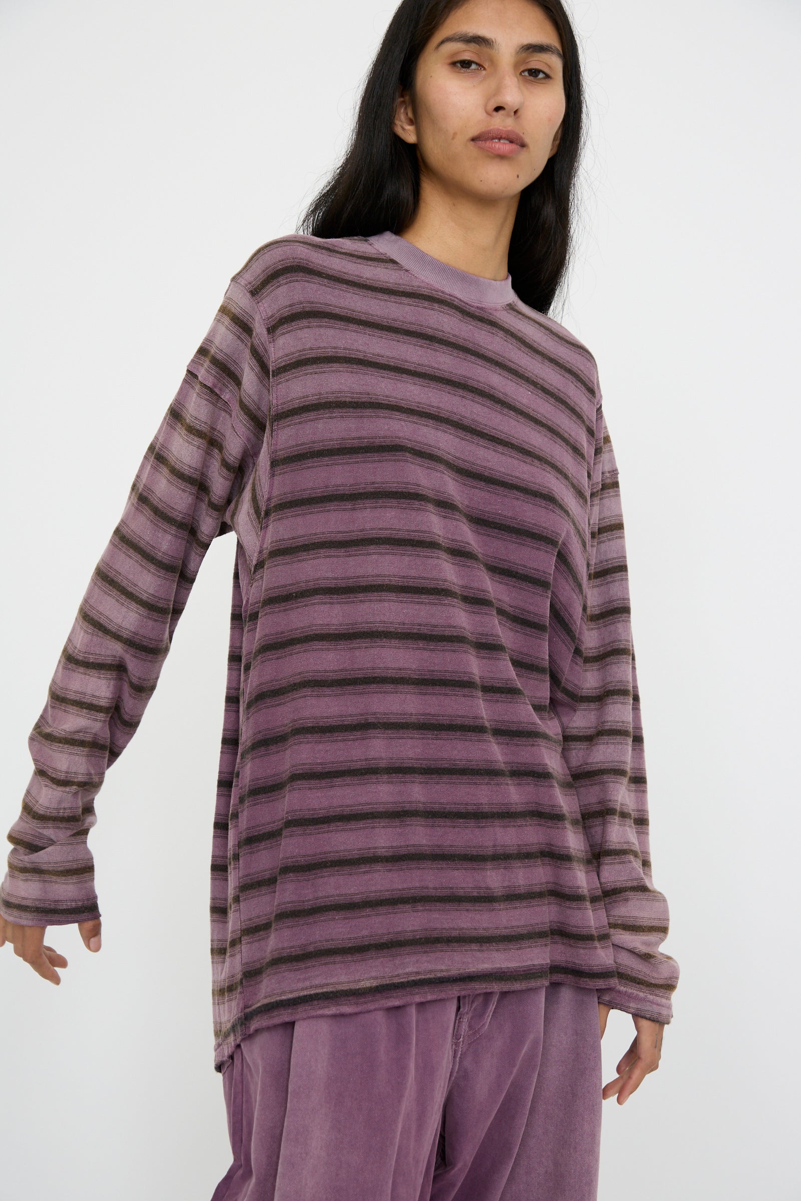 A person in Dr. Collectors' Hemp and Cotton Derrick Tee Stripes in Sunfaded Mauve, with matching purple pants, standing against a plain white background.