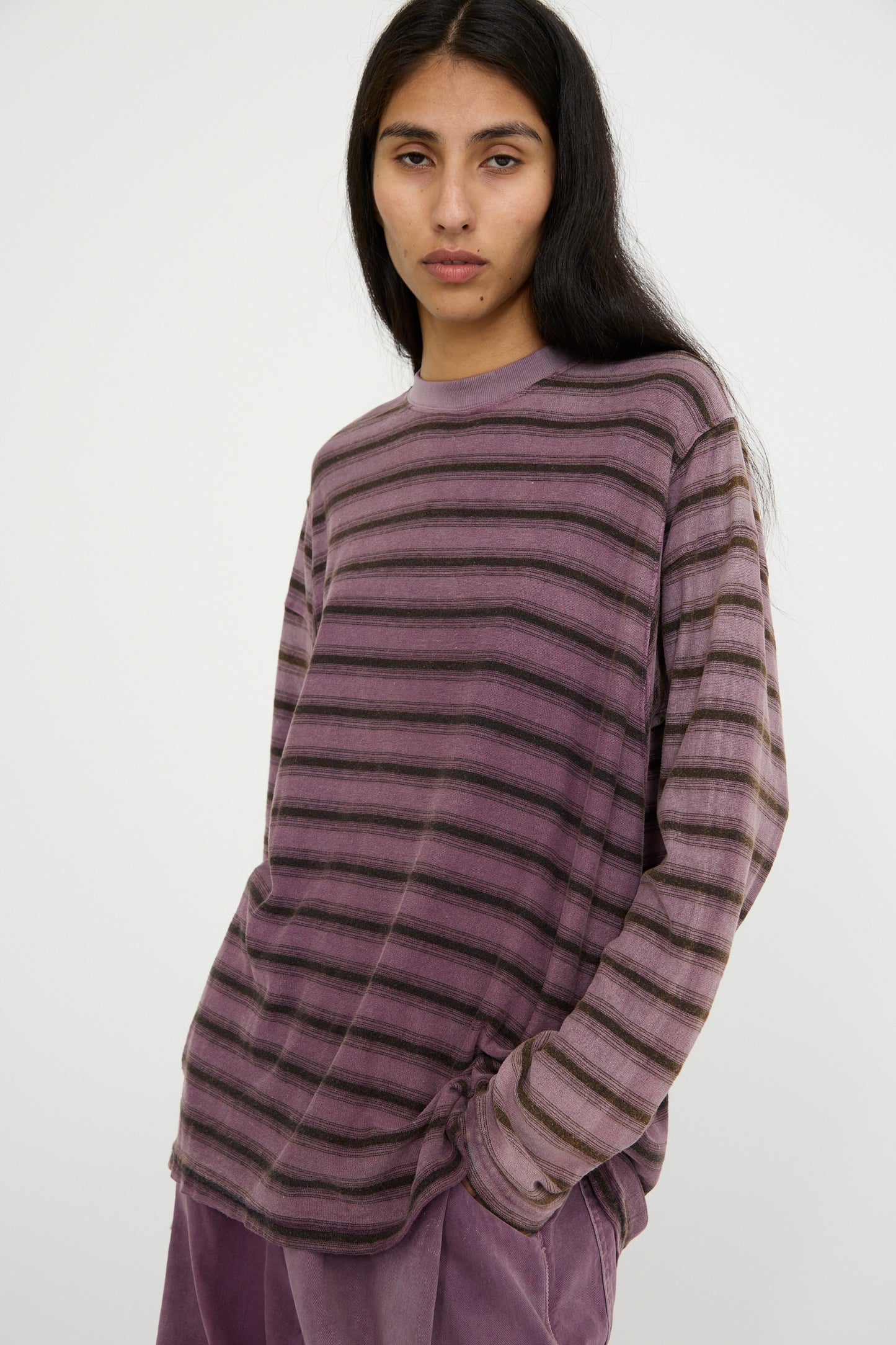 A person wearing the Hemp and Cotton Derrick Tee Stripes in Sunfaded Mauve, designed by Dr. Collectors, stands against a plain background and looks foward.