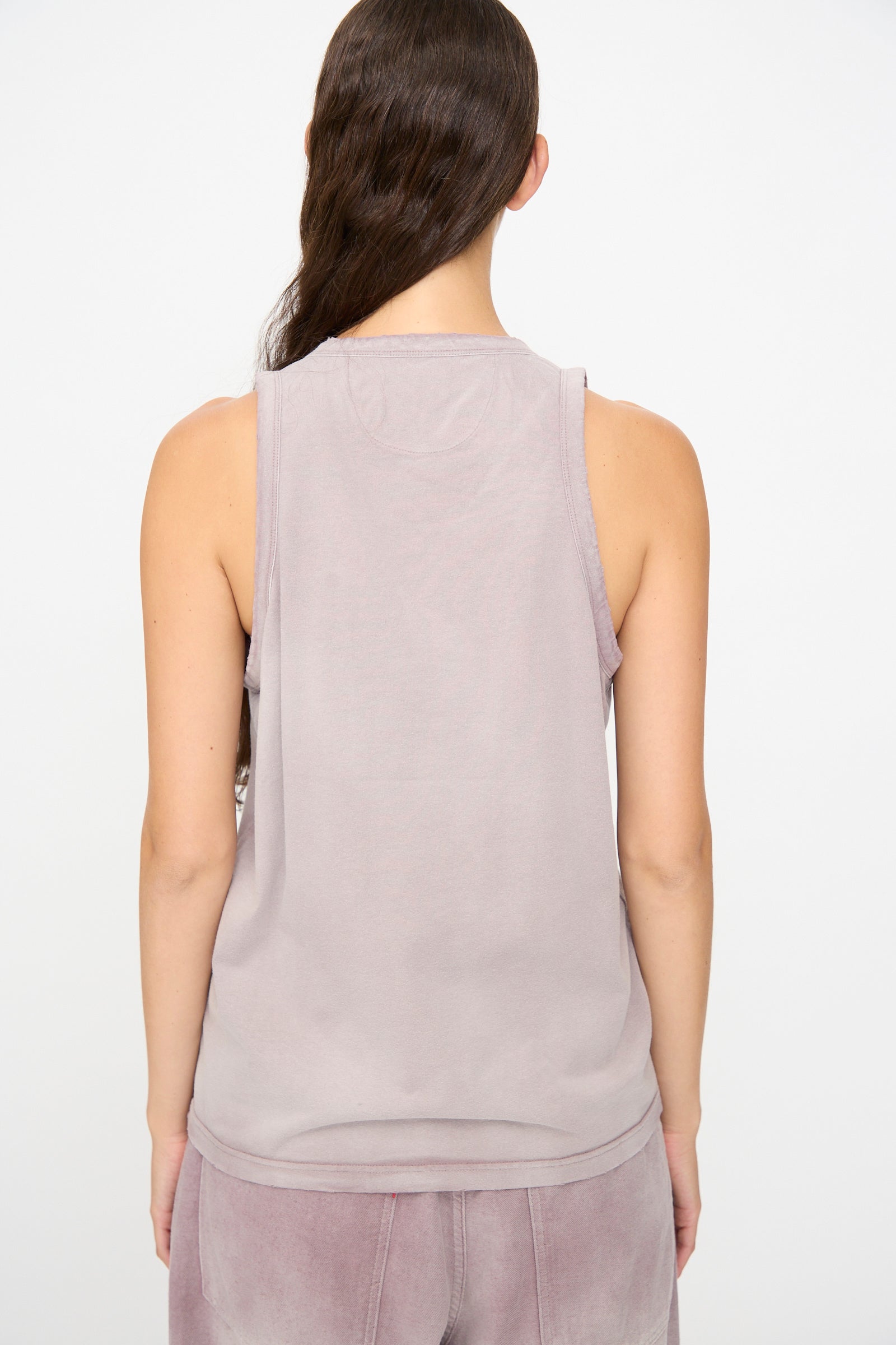 A person stands with their back to the camera, wearing the Dr. Collectors Marcel Tank in Sunfaded Dusty Orchid and matching velour pants against a plain white background.