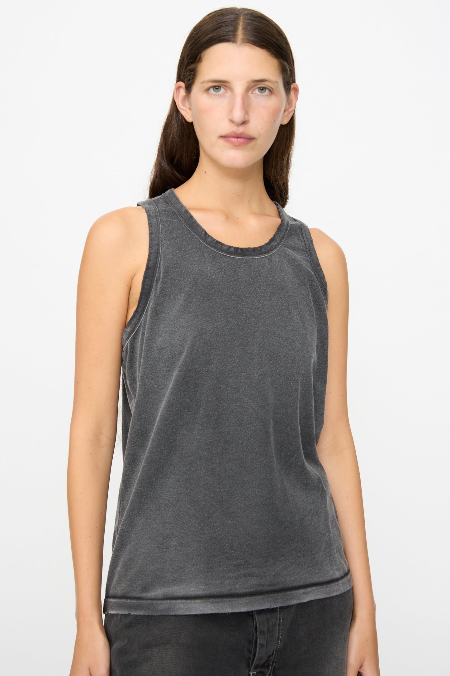 A person with long brown hair wears the Dr. Collectors Marcel Tank in Sunfaded Smoke Black, styled with black jeans and standing against a plain light background.