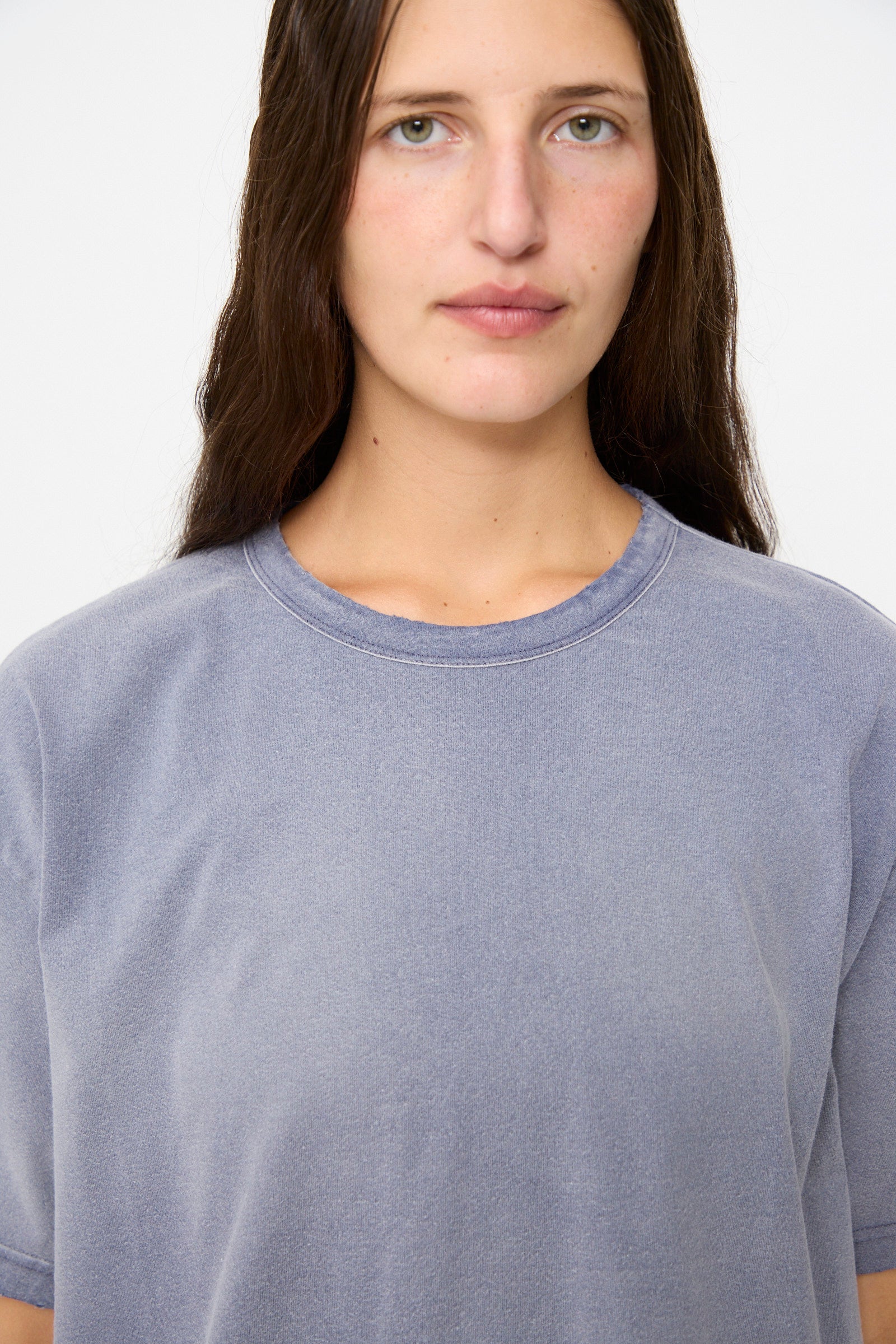 A person with long brown hair is facing the camera against a plain white background, wearing the Dr. Collectors Model T tee in Sunfaded Navy in a loose fit.