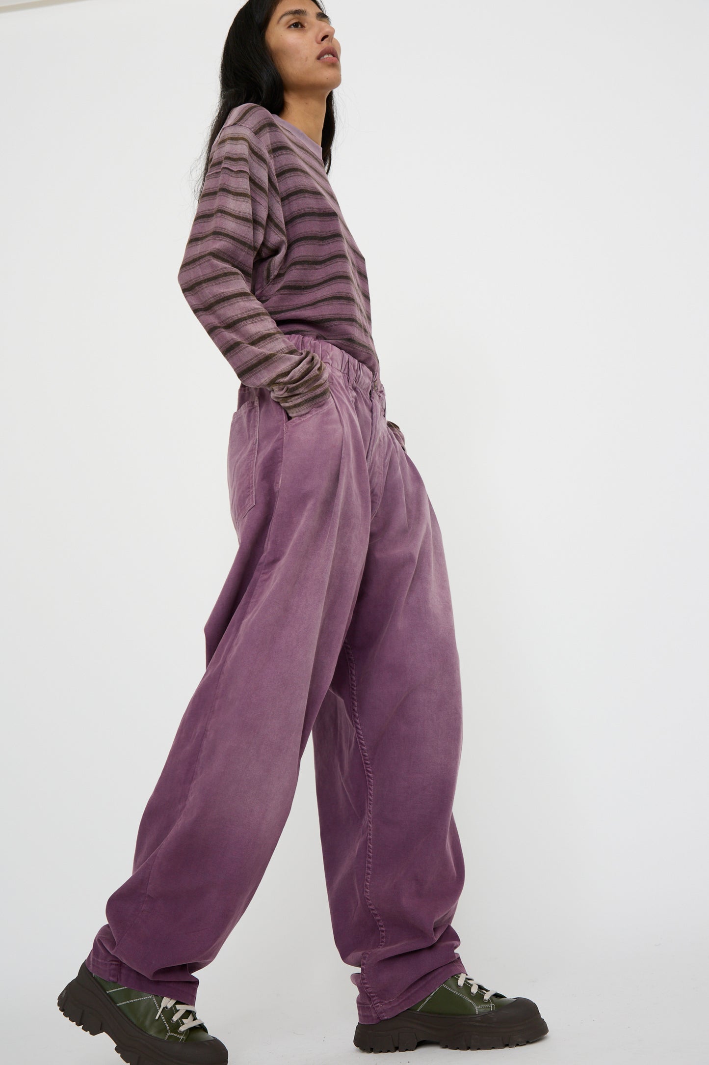 A person is wearing a striped sweater and oversized P40 Z Boy's Twill Pant in Sunfaded Mauve from Dr. Collectors, made of Japanese cotton, with their hands in the pockets, standing against a plain background.