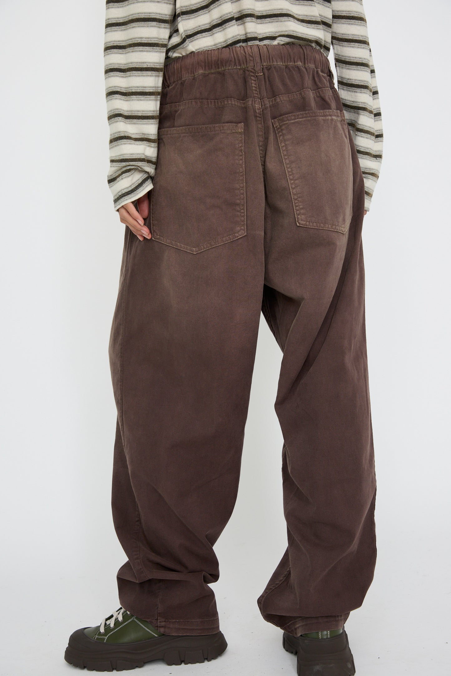 A person in striped long-sleeve shirt with Dr. Collectors' P40 Z Boy's Twill Pant Sunfaded in Cappuccino. These pants are crafted from Japanese cotton and feature a relaxed fit with an elasticated waistband and noticeable back pockets, shown against a white background. 