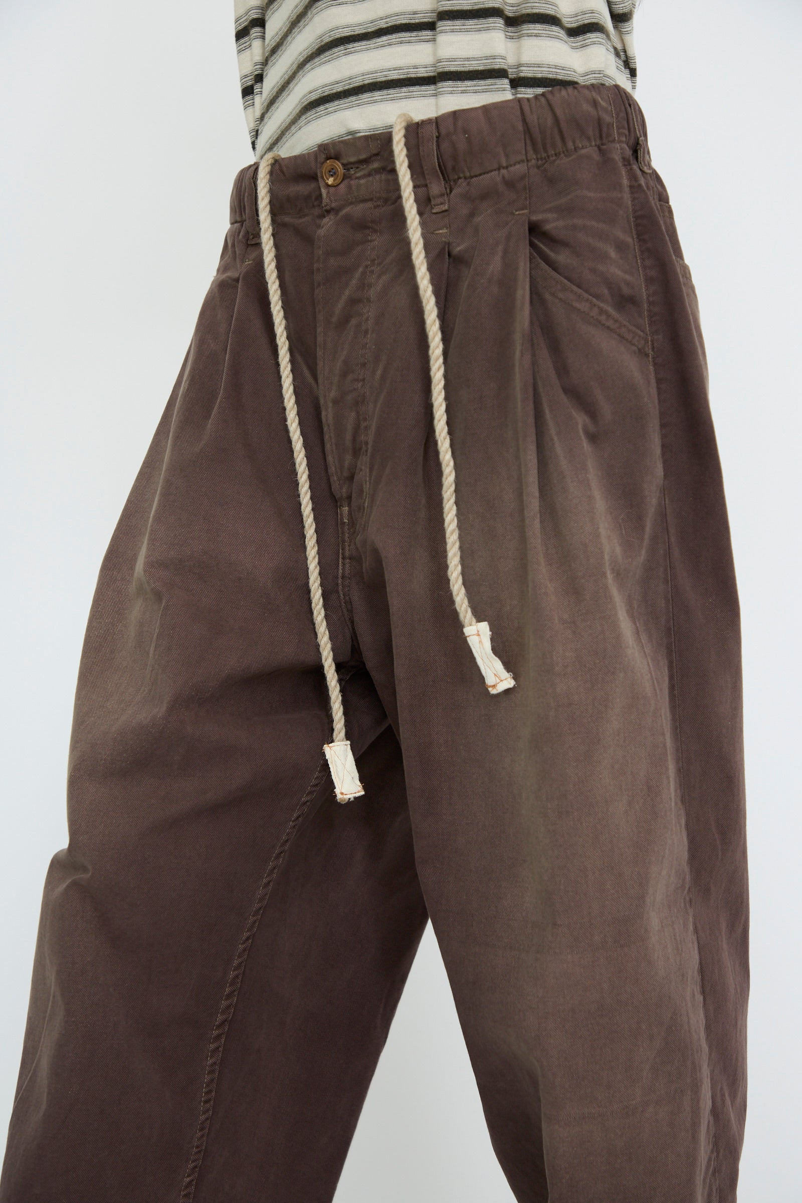 A person wearing a striped shirt and the P40 Z Boy's Twill Pant Sunfaded in Cappuccino by Dr. Collectors, featuring an elasticated waistband with a drawstring.