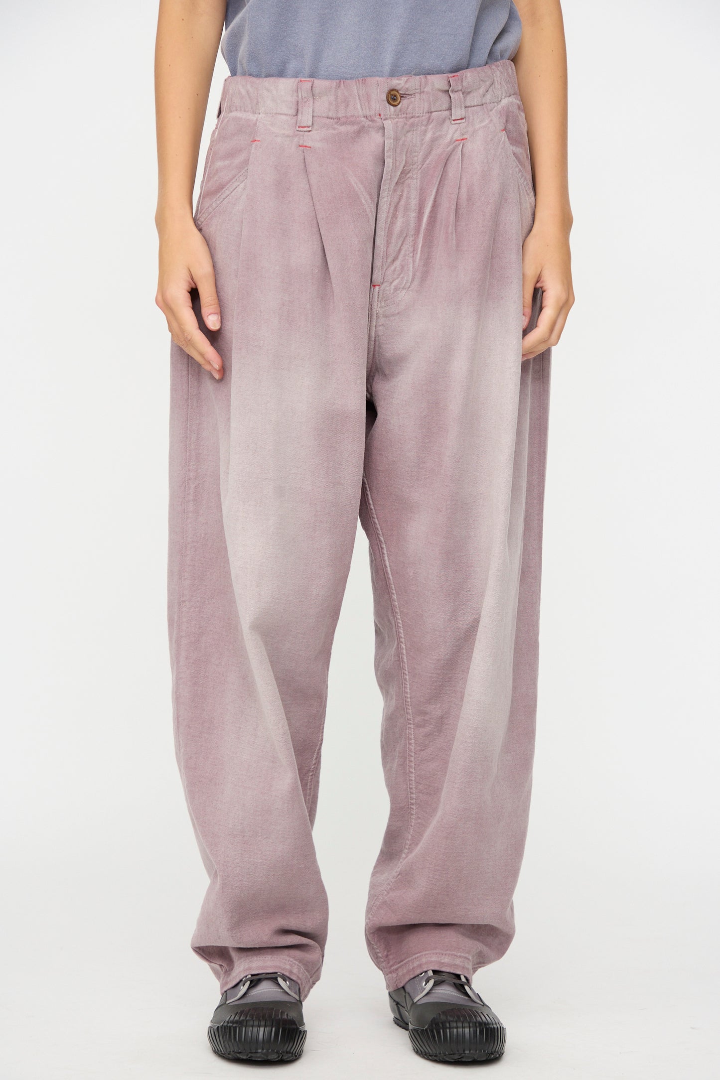 A person wearing the Dr. Collectors P40 Z Boys Pant in Sunfaded Dusty Orchid, a relaxed fit, pleated pant crafted from Japanese cotton corduroy, stands against a plain white background.