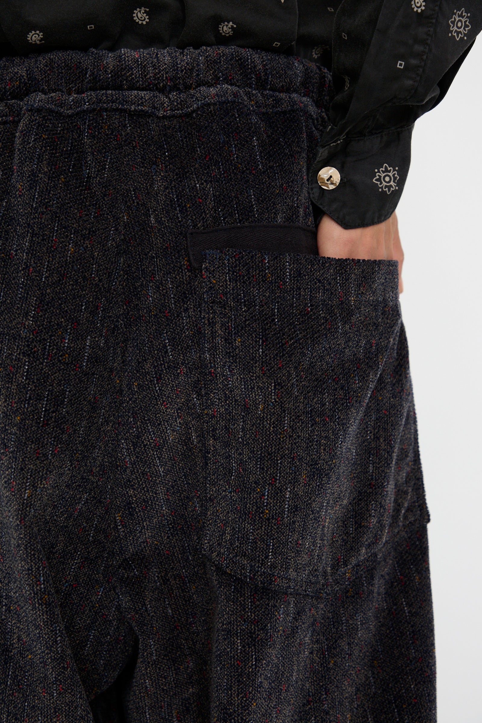 Close-up of someone wearing the Dr. Collectors P43 Kyoto Corduroy Japanese Dobby Tweed Pant in Black with an elasticated waist with their hand in the back pocket. 