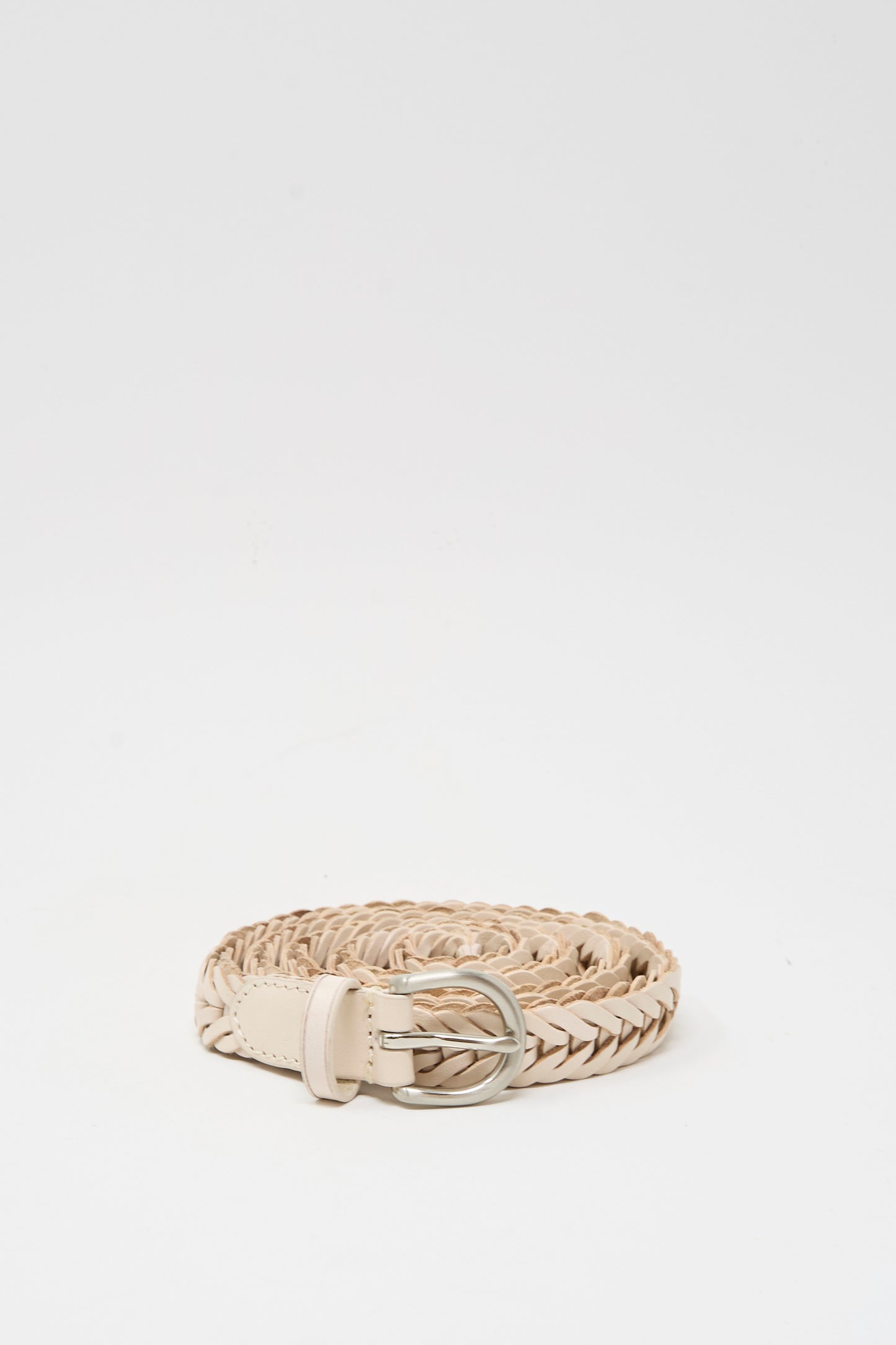 The Dragon Diffusion Brass Buckle Single Link Belt in Sand, a handcrafted braided leather belt with a brass buckle, is coiled neatly on a plain white background.